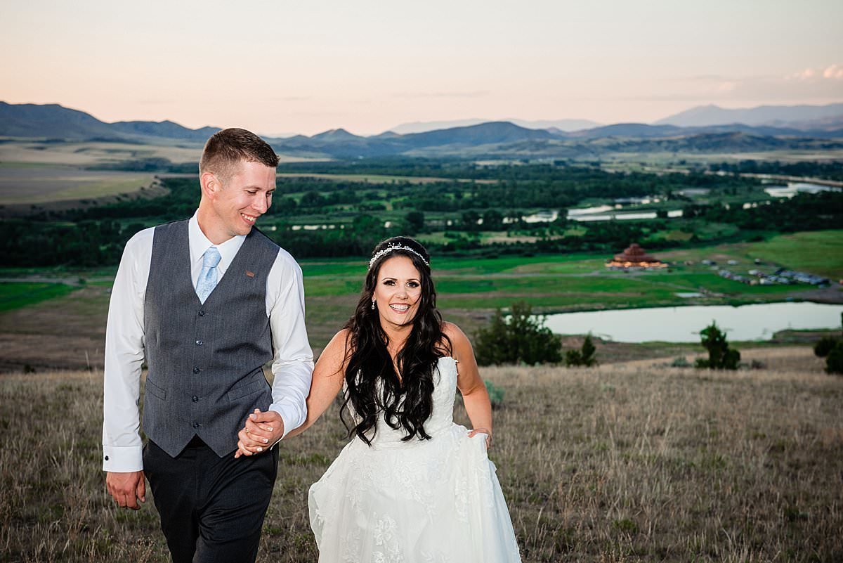 Couple holding hands and walking together up a hillside with Headwaters Ranch in the valley below