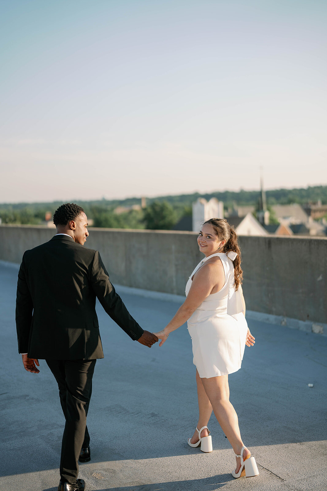 Romantic rooftop engagement photo of couple walking together in Kalamazoo, MI.