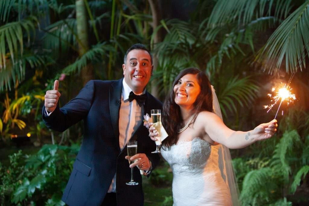 A groom giving a thumbs up as his bride holds out a sparkler