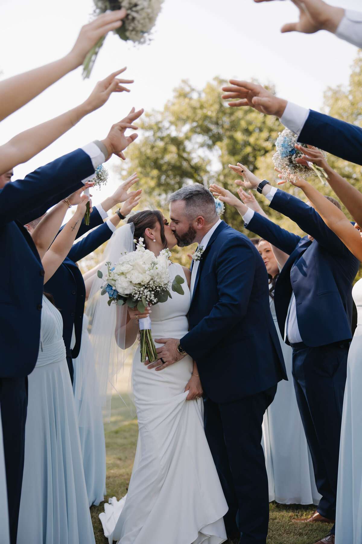 full wedding party portraits with bride and groom kissing