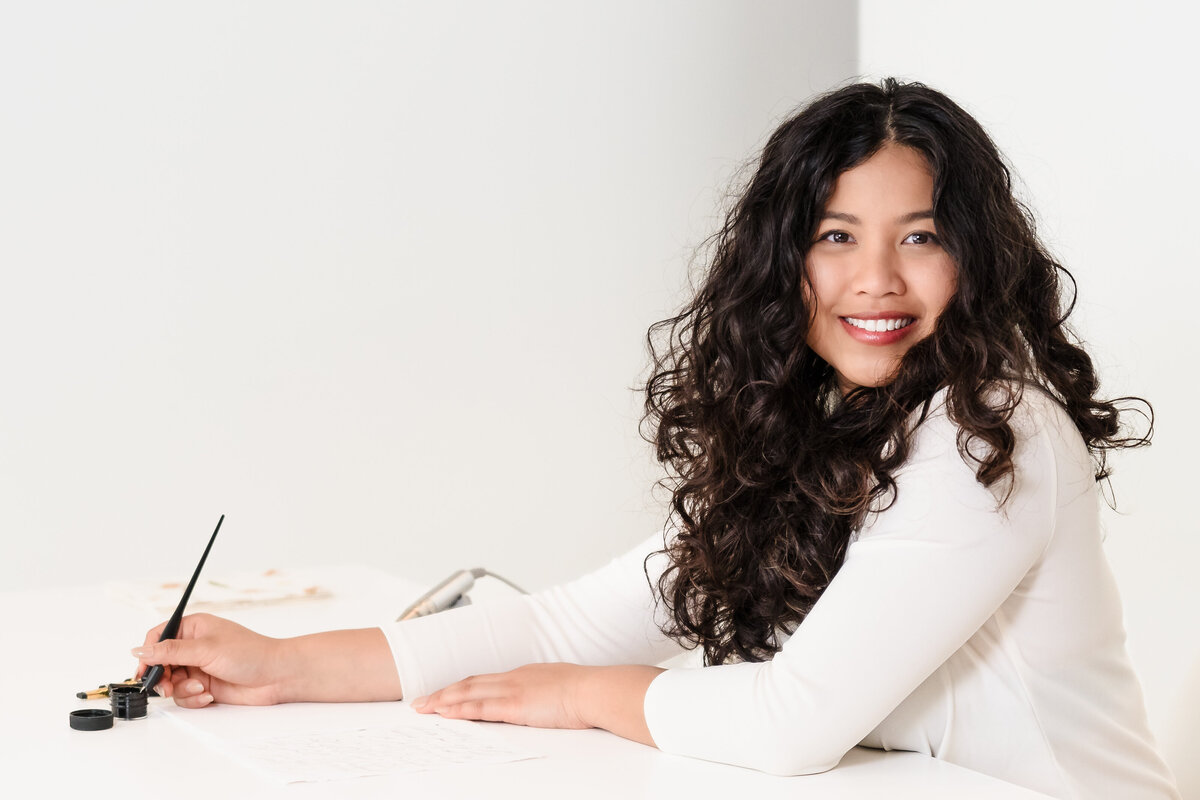 brand photo of a calligrapher looking at the camera and smiling