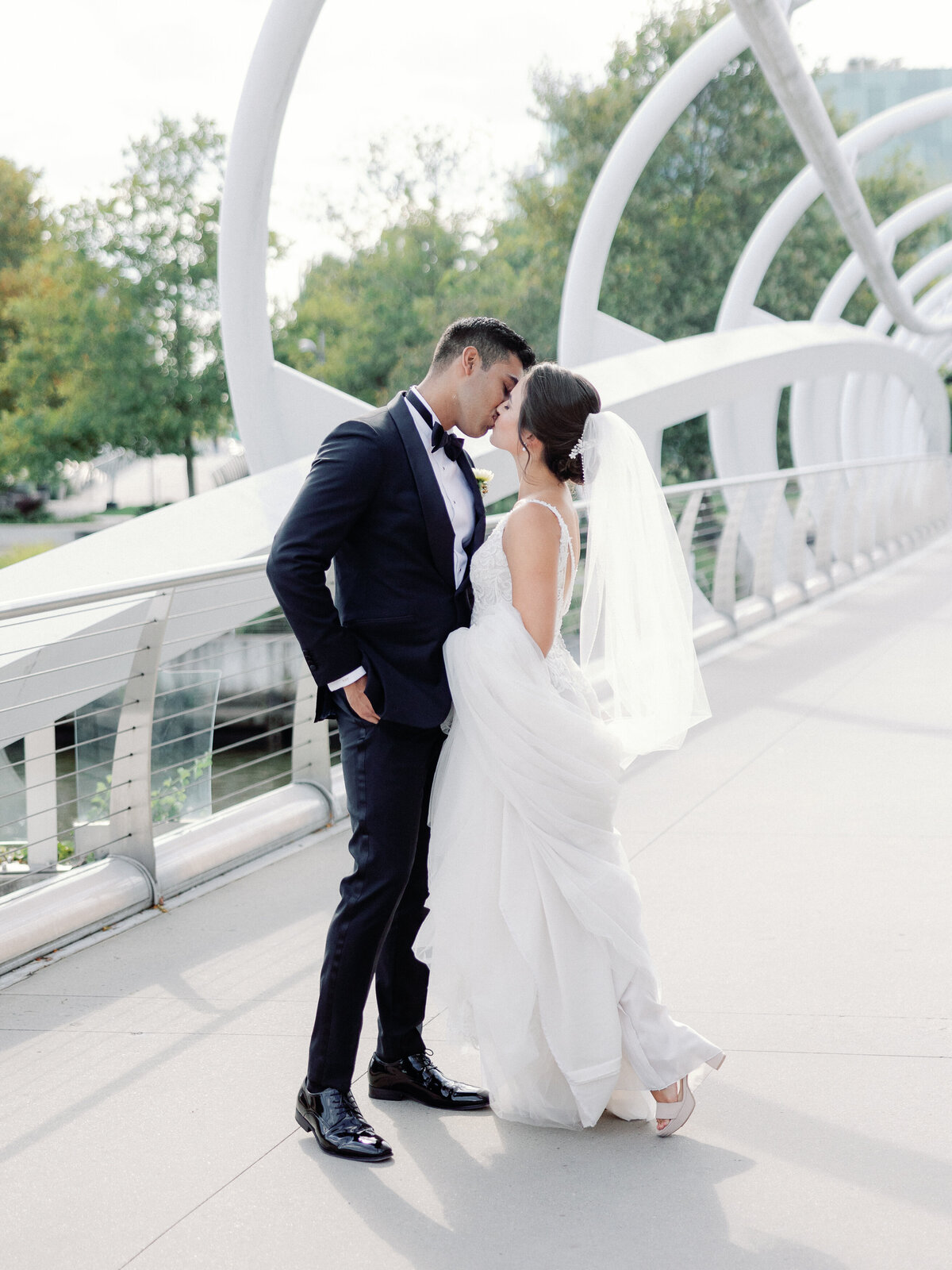 A bride and groom share a kiss on the yards park bridge in dc