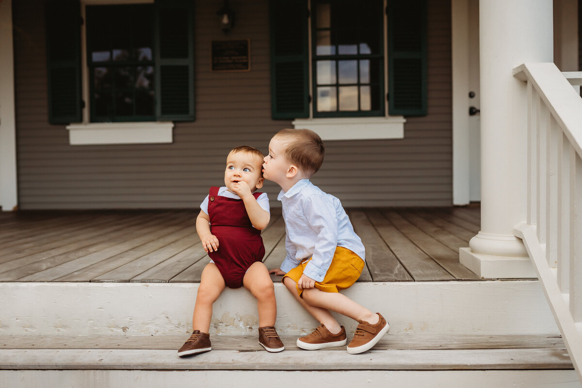 Little boy kissing younger brother on steps
