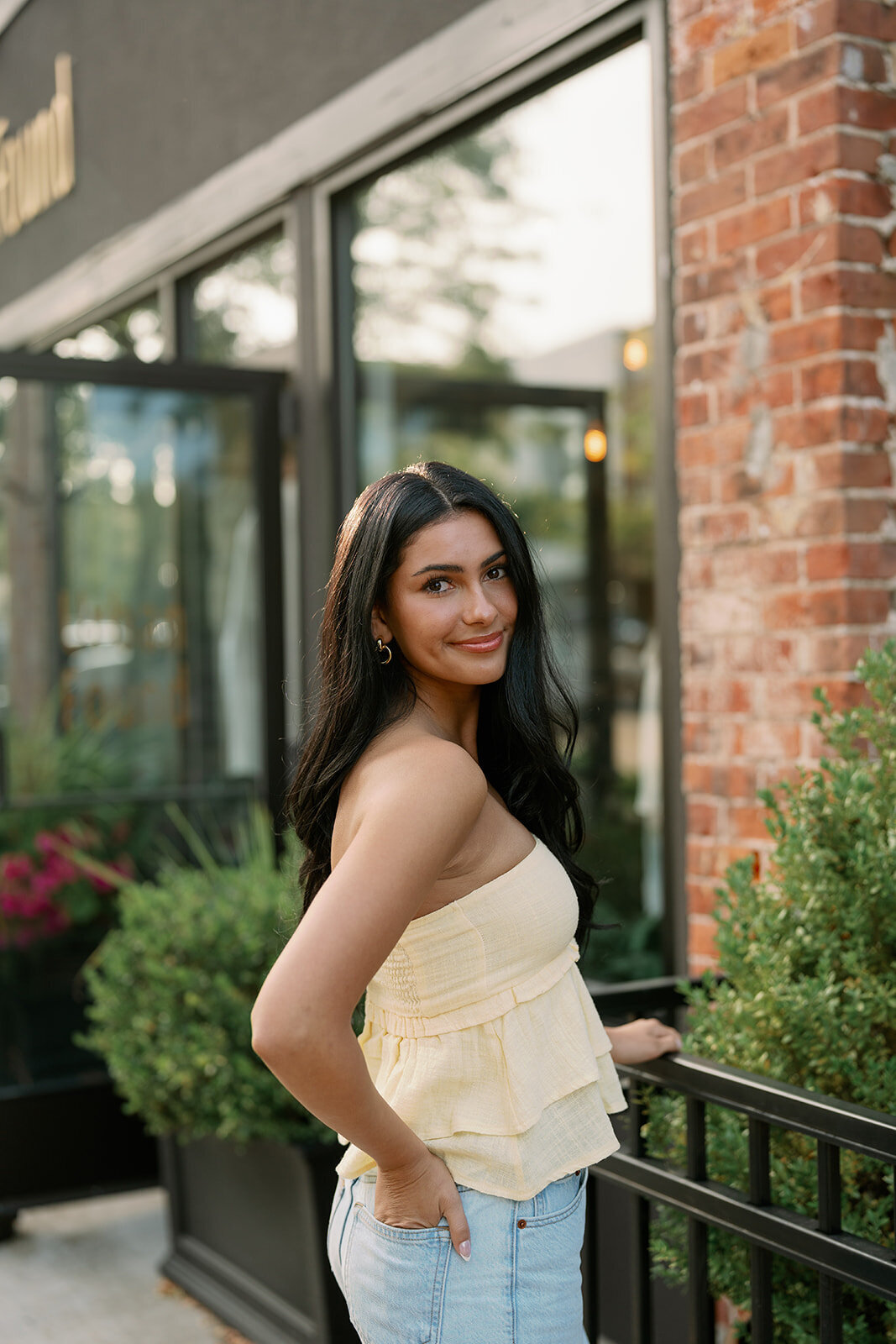 Teen girl leaning against a brick storefront during her downtown South Haven senior photo session.