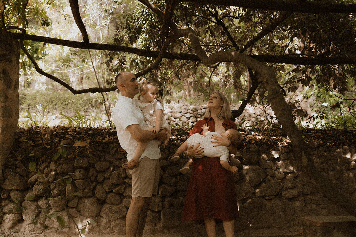 photo famille maman qui allaite bebe dans les bras et papa porte sa fille dans les jardins de la serre de la madone menton