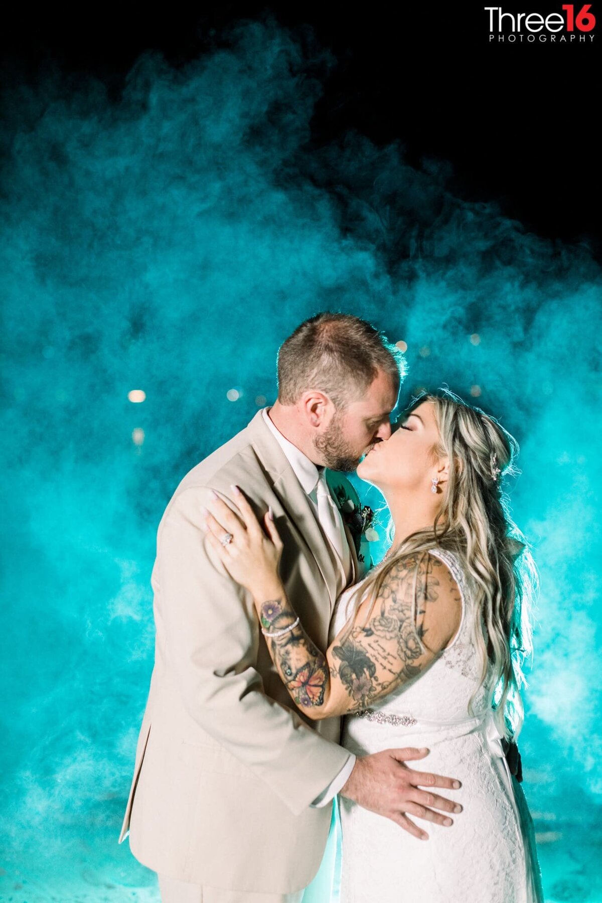 Bride and Groom share a tender kiss with a blue mist behind them
