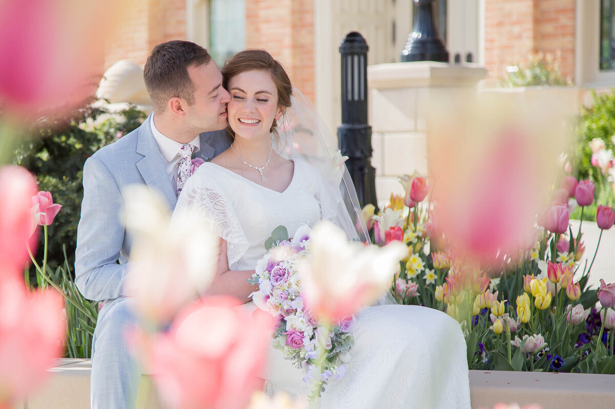 A wedding couple behind tulips enjoying a moment on their wedding day