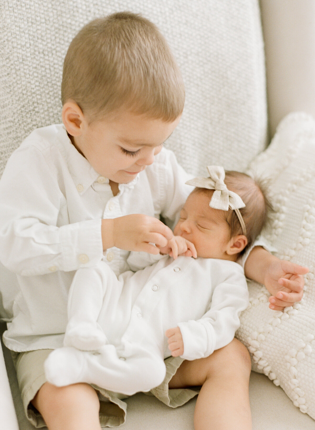 Big brother holds baby sister's fingers during a newborn photo session in Raleigh. Photographed by newborn photographer Raleigh A.J. Dunlap Photography.