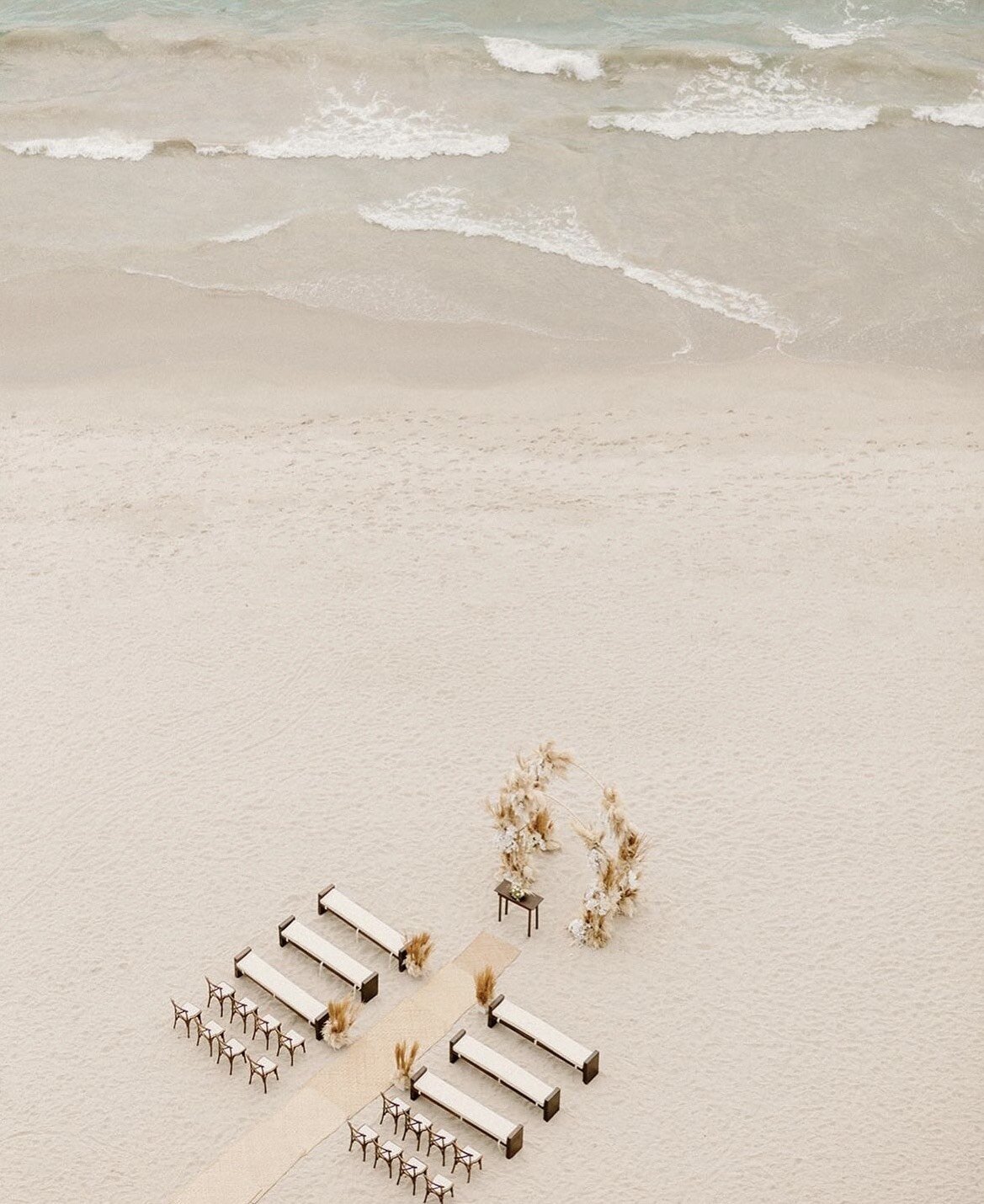 A dreamy beach wedding altar ready for guests, perfect for couples booking wedding mobile hair and makeup services for destination celebrations.