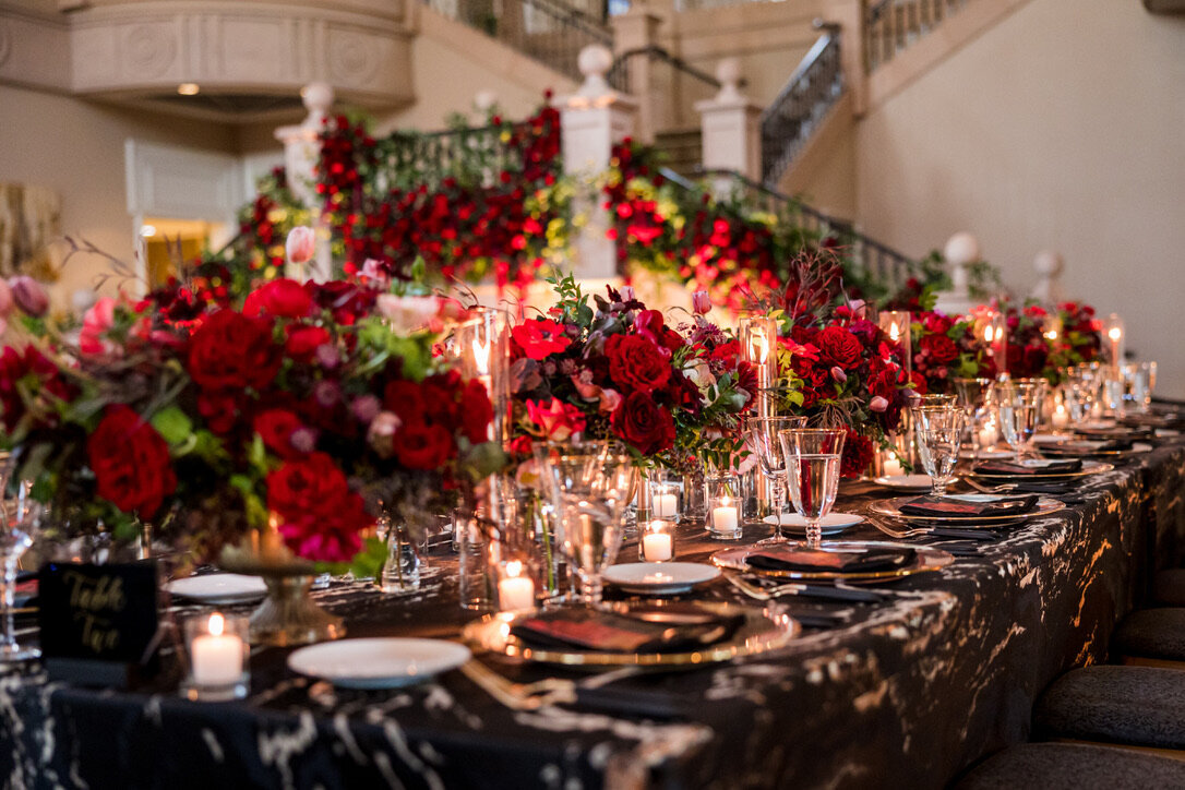 oblong arrangements, candle light, gold footed dishes, tea lights, black and white linens, gold rimmed glassware, black matte flatware, gold chairs, tall arrangements, kings tables, champagne drapery