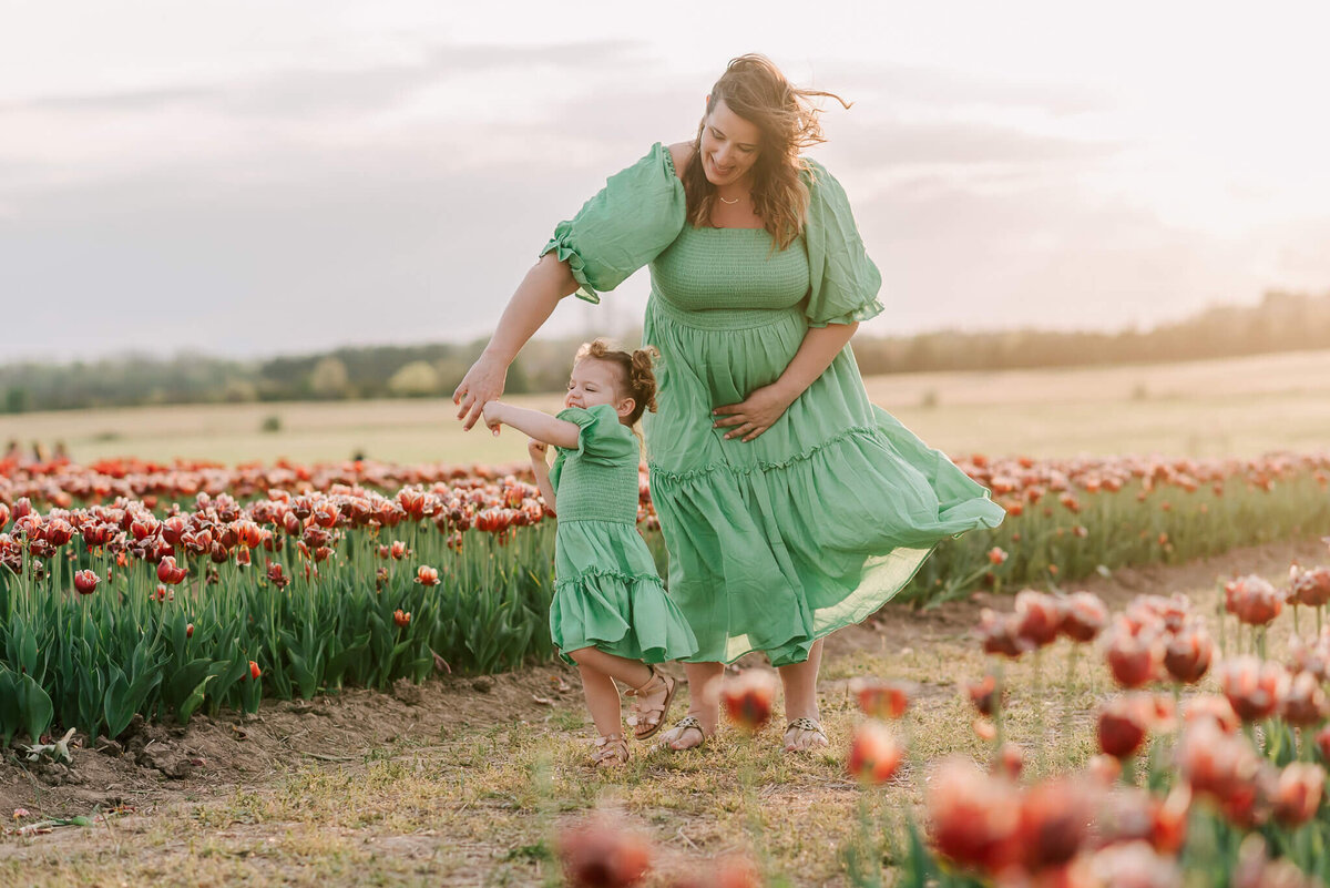 A woman and daughter wearing green dresses dancing among the tulips at Burnside Farms