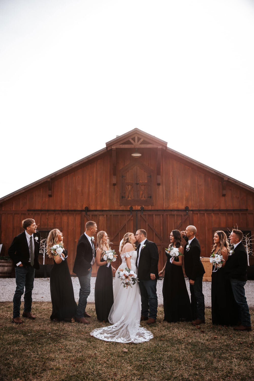 Bride and groom with their wedding party in front of the rustic barn