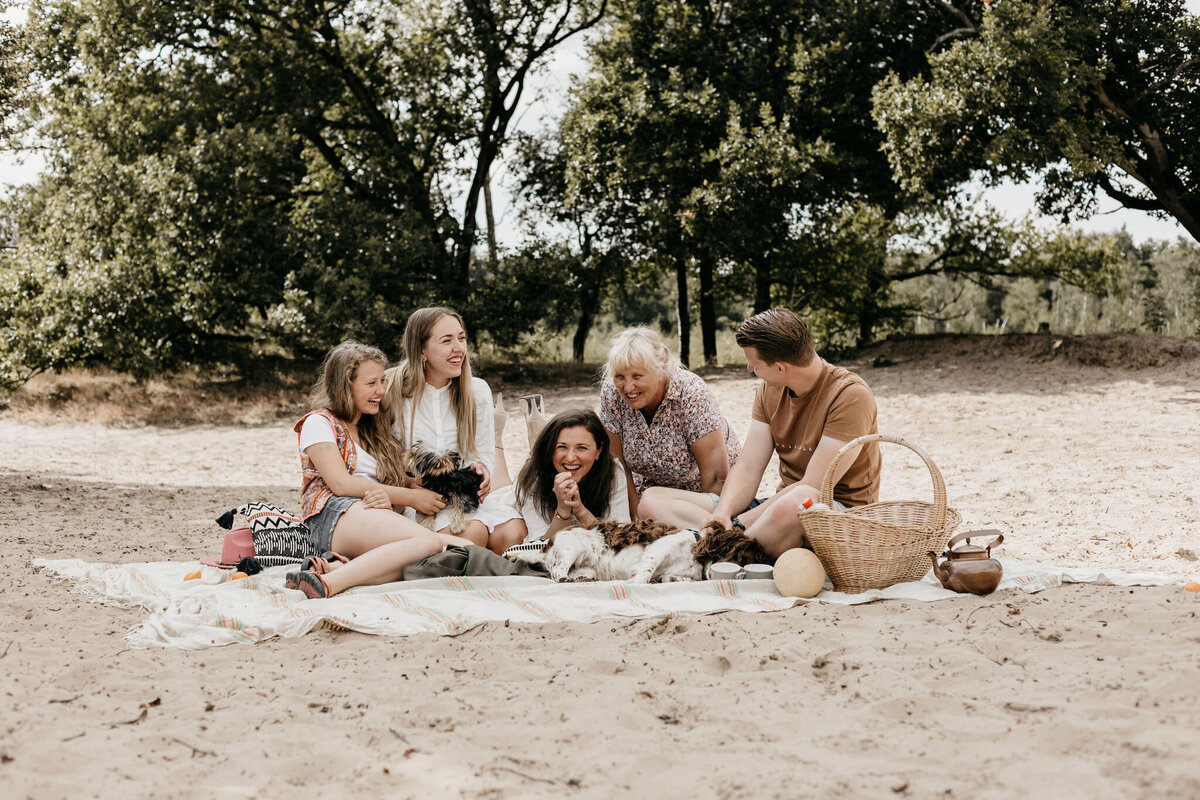 Spontane gezinsfoto van een gezin op picknickkleed tijdens hun gezinsshoot in Drenthe