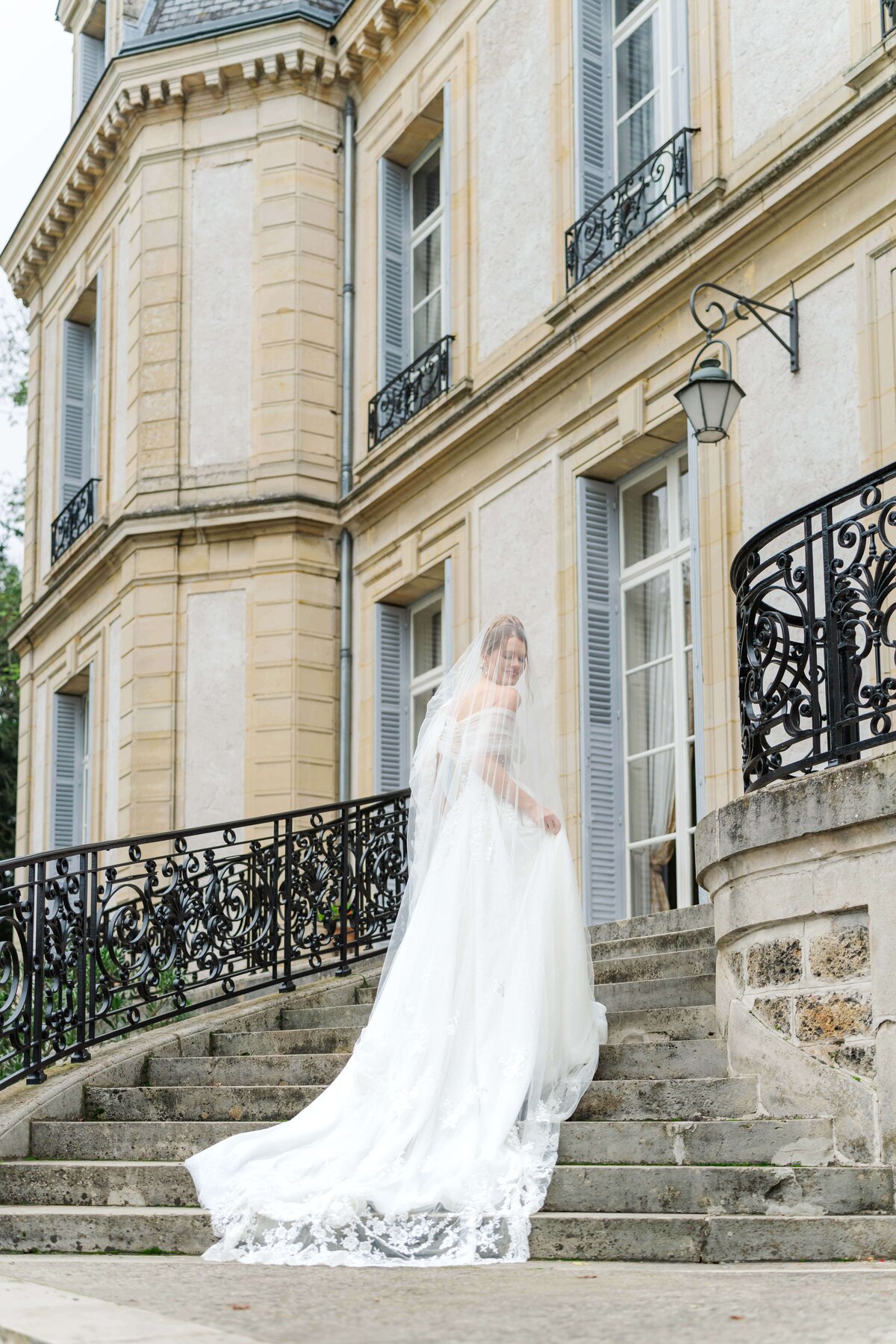 bride walking up stairs looking back at the camera with the vail over her