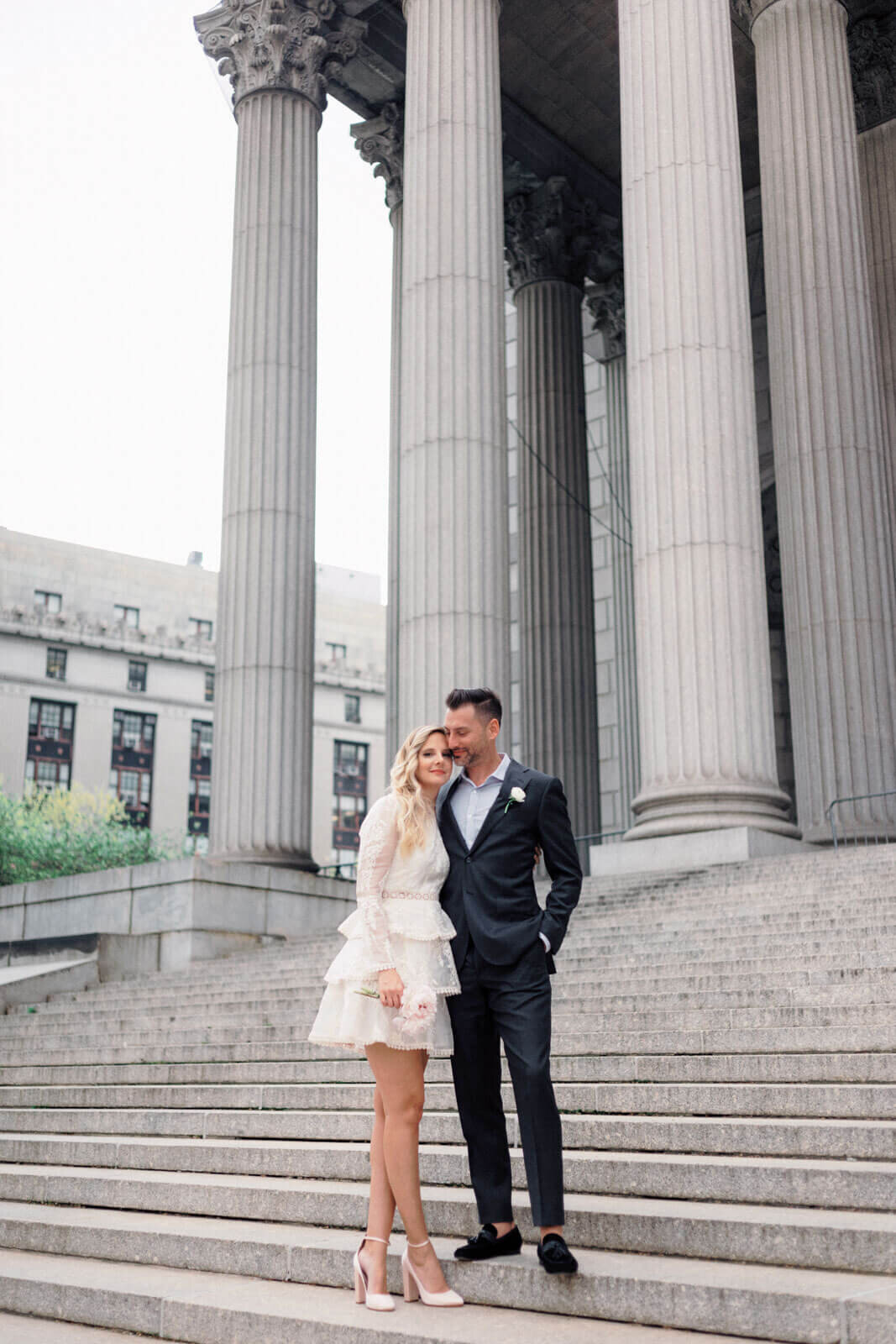 The eloping bride and groom are happily standing on the grand staircase of the NY City Hall. Image by Jenny Fu Studio