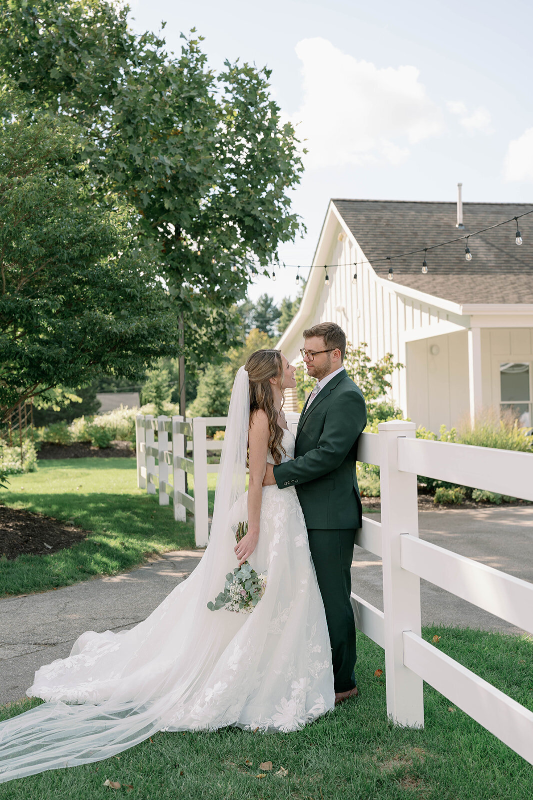 Couple smiling at each other while leaning against a white railing with The Ivy House venue in the background.