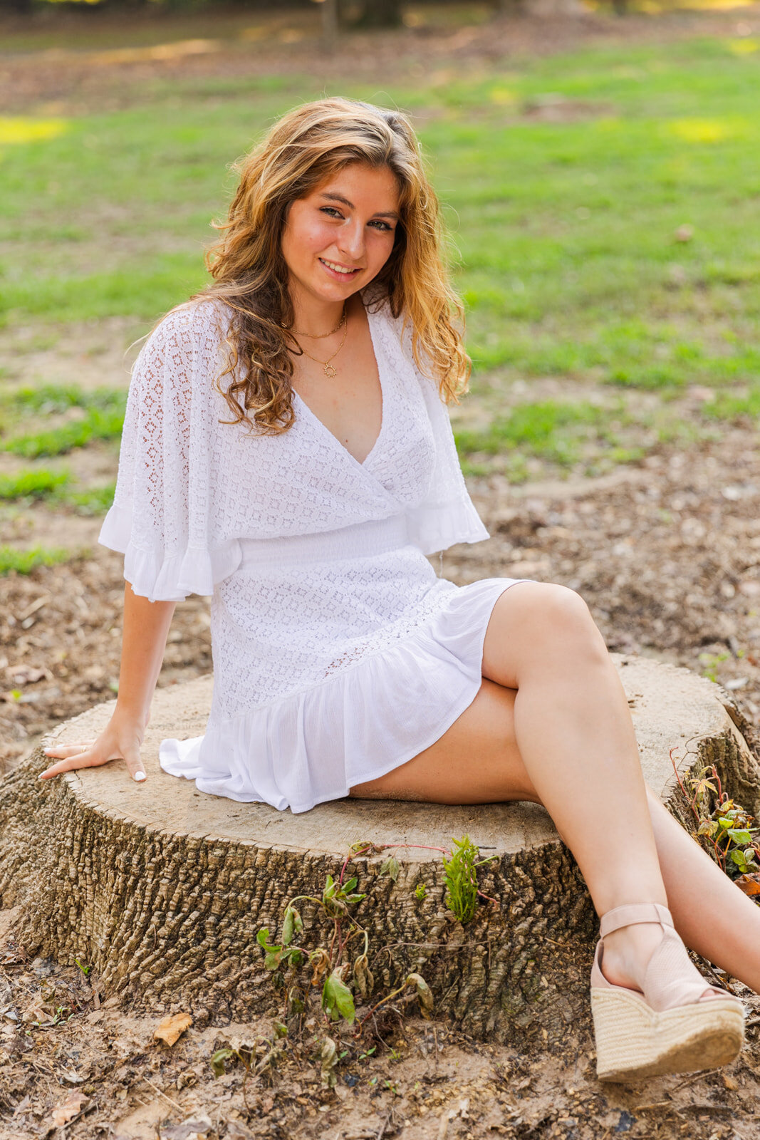 senior girl sitting in the middle of a park resting on her arms during photoshoot