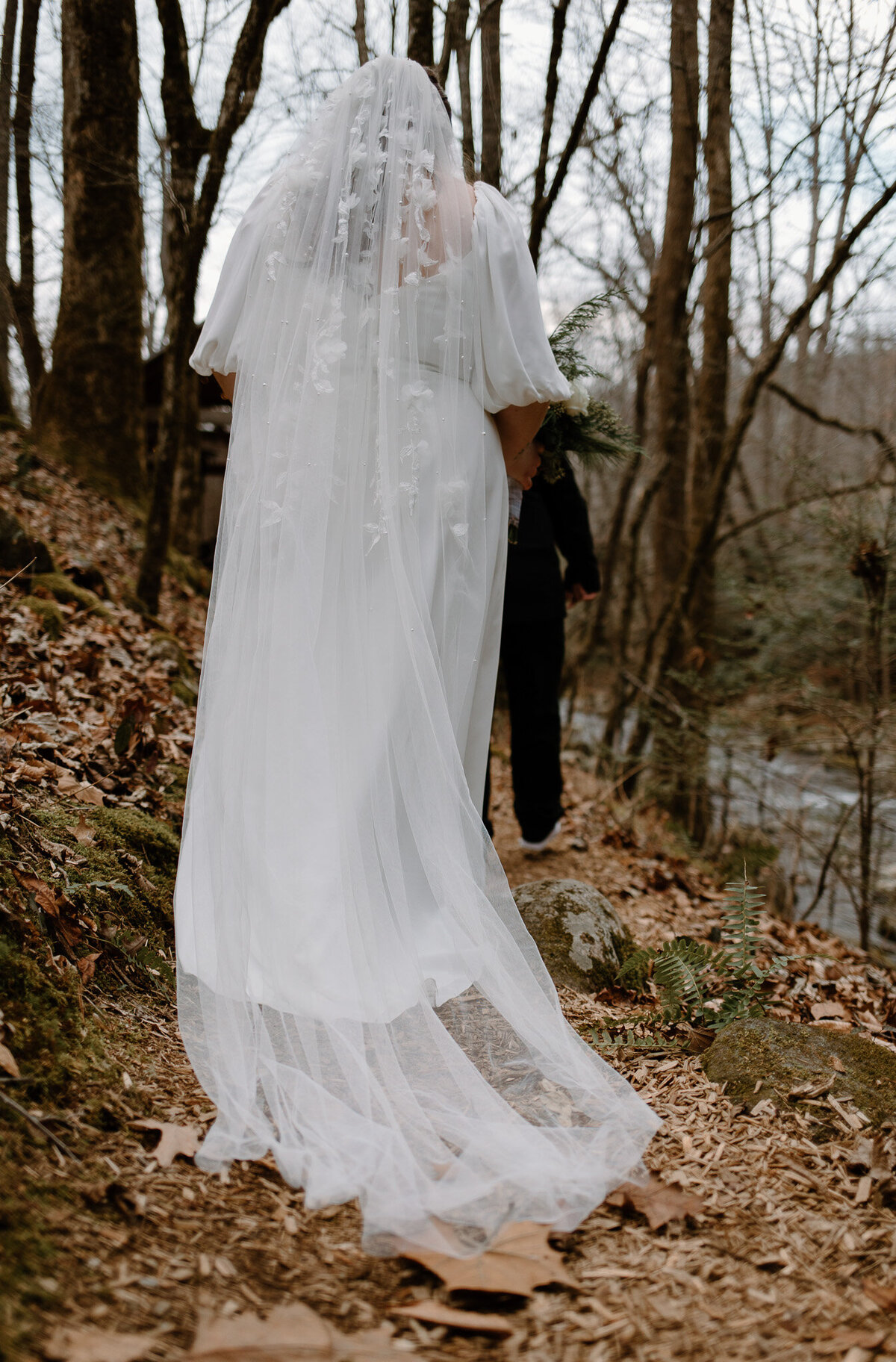Detail shot of the bride's veil trialing behind her as she walks through the woods at her forest elopement in the Smoky Mountains.