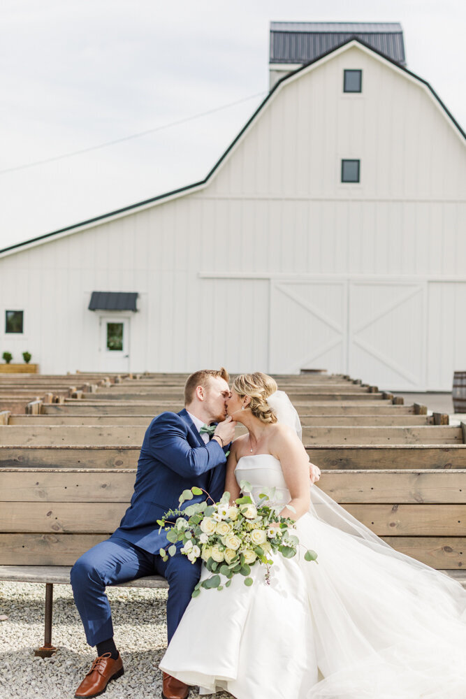 bride and groom kissing while sitting on a wooden pew