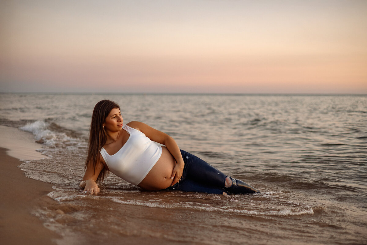 Newborn baby girl wrapped in white, held by smiling parents during a Grand Rapids, MI newborn photography session at Honeywild’s cozy studio.