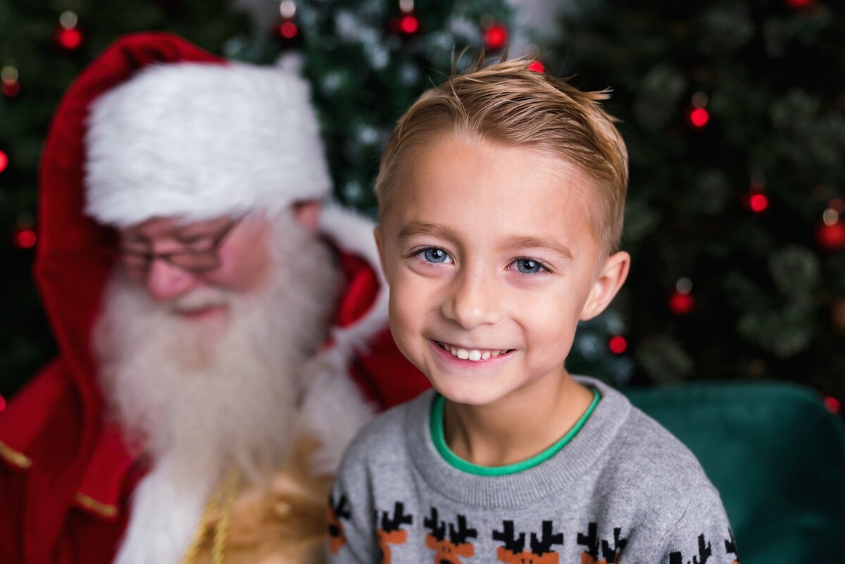 Smiling boy close up with Santa in the background