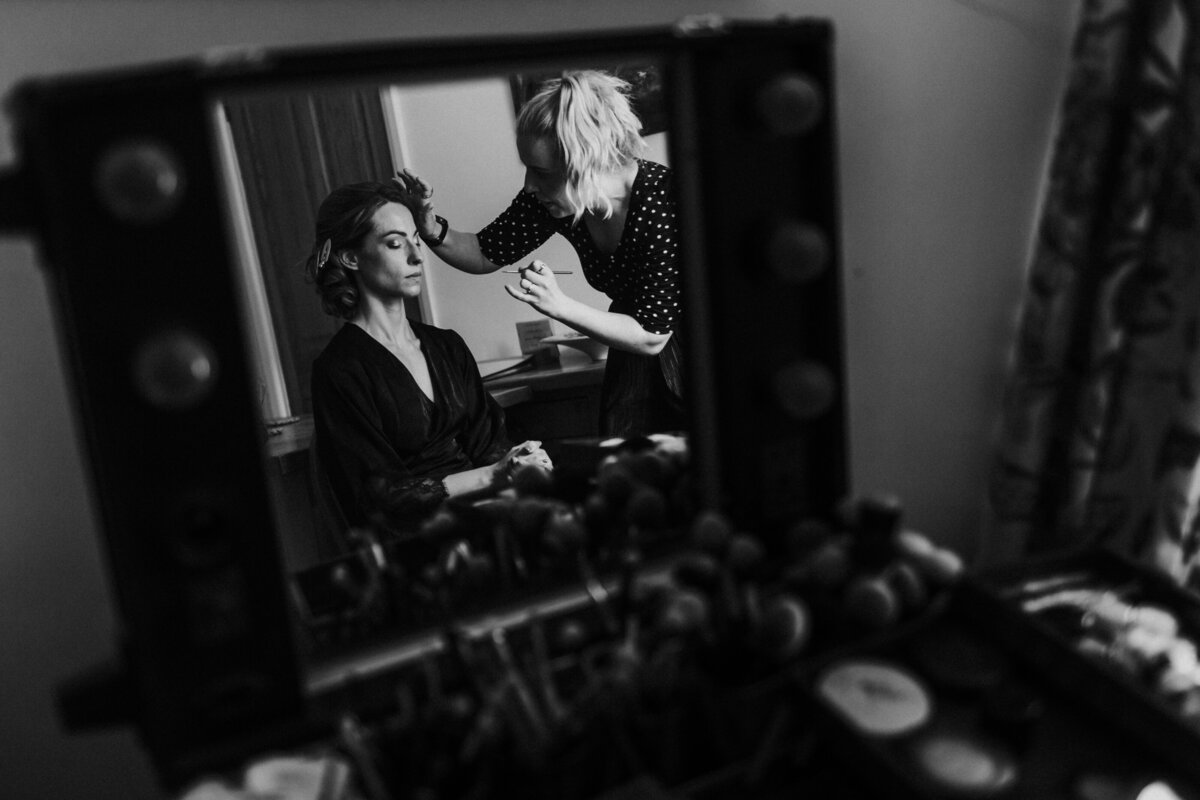 Artistic black and white photo of bride having make up done in Devon