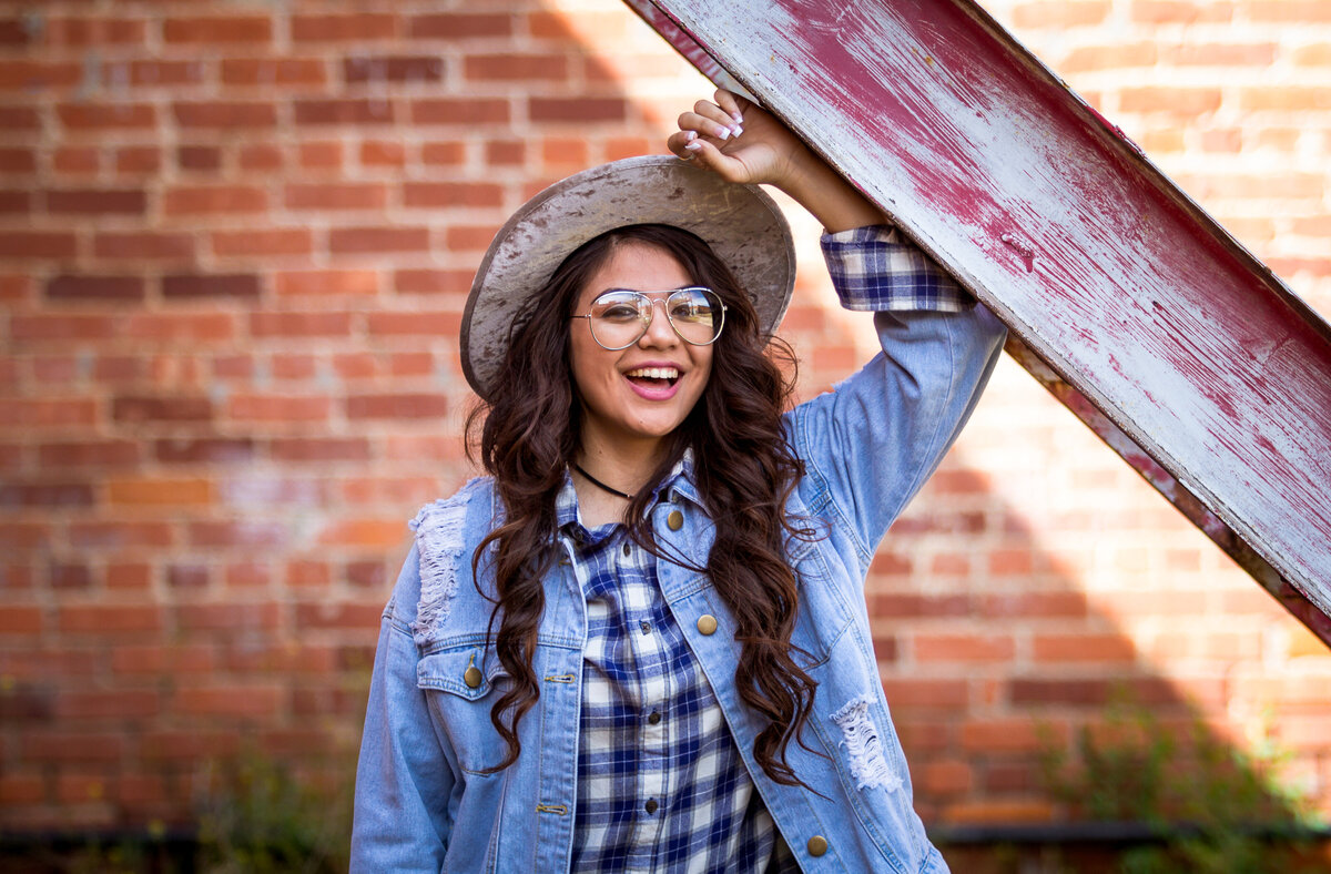 Senior girl standing smiling with hat and glasses in downtown Plainview tx