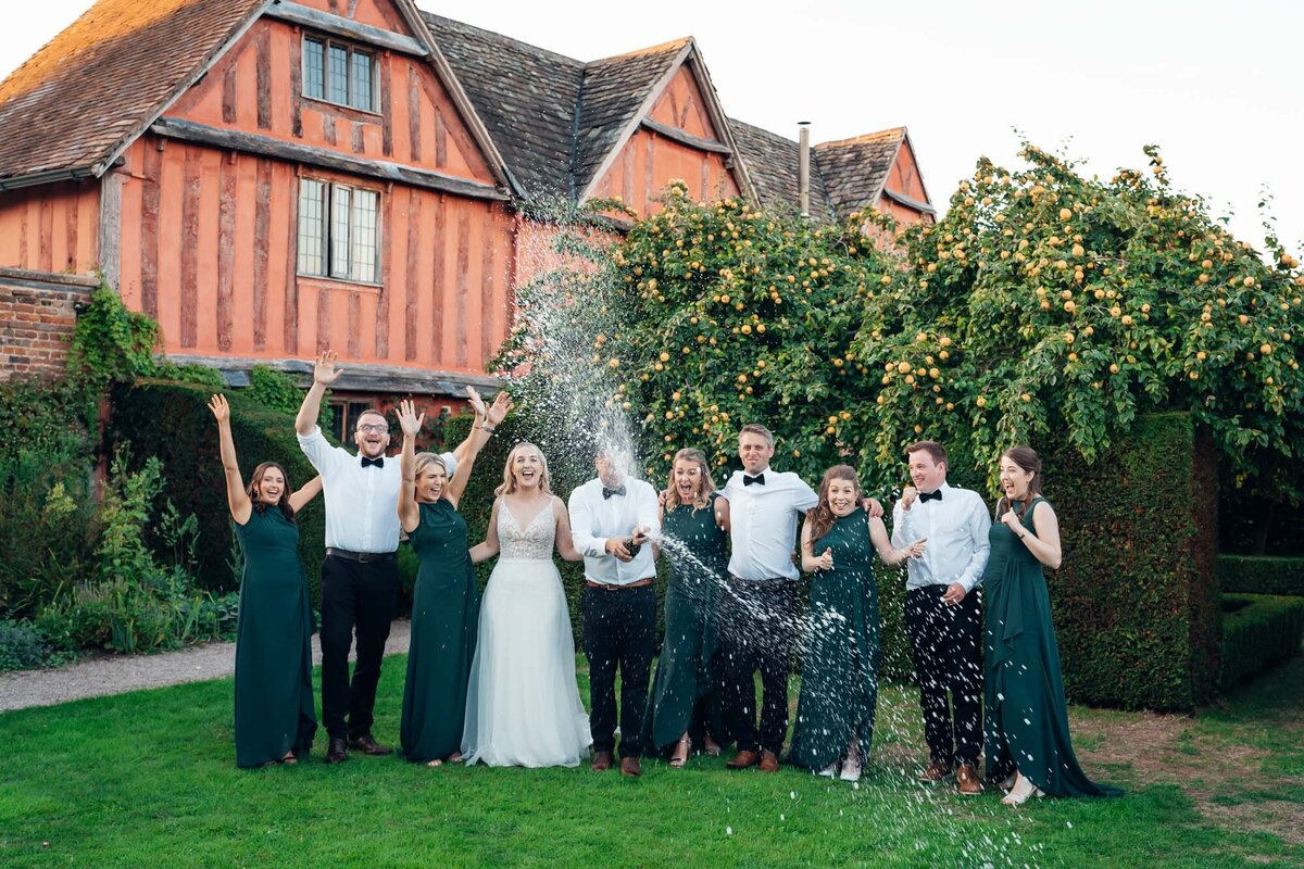 cotswold-wedding-photographer-wedding-party-spraying-champagne