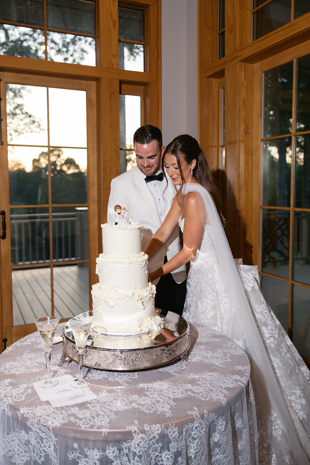 Couple cuts a three-tier white wedding cake during reception at Old Edwards Inn in Highlands, North Carolina.