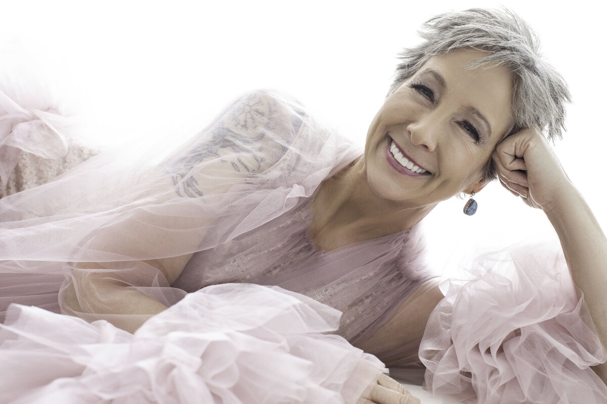 A woman with silver hair and a pink robe dress lies down and poses for a portrait at Janel Lee Photography Studios Cincinnati Ohio