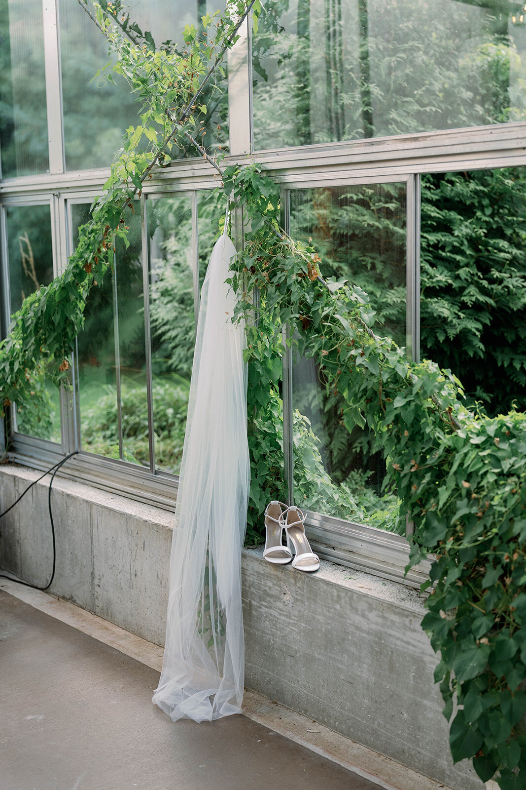 Detail shot of the bride’s veil and shoes styled inside the Ivy House greenhouse.
