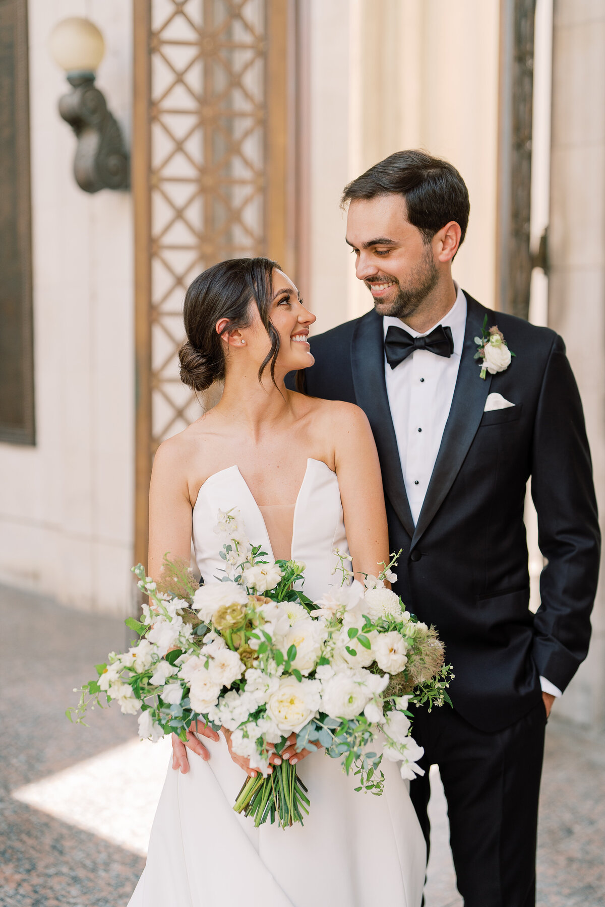 Whimsical bridal bouquet in cream, white, taupe, and champagne colors. This summer wedding bouquet is full of fun texture and represents elegant and timeless floral design. Composed of roses, lisianthus, smoke bush, ranunculus, and natural greenery. White and green floral wedding in downtown Nashville. Design by Rosemary & Finch Floral Design in Nashville, TN.