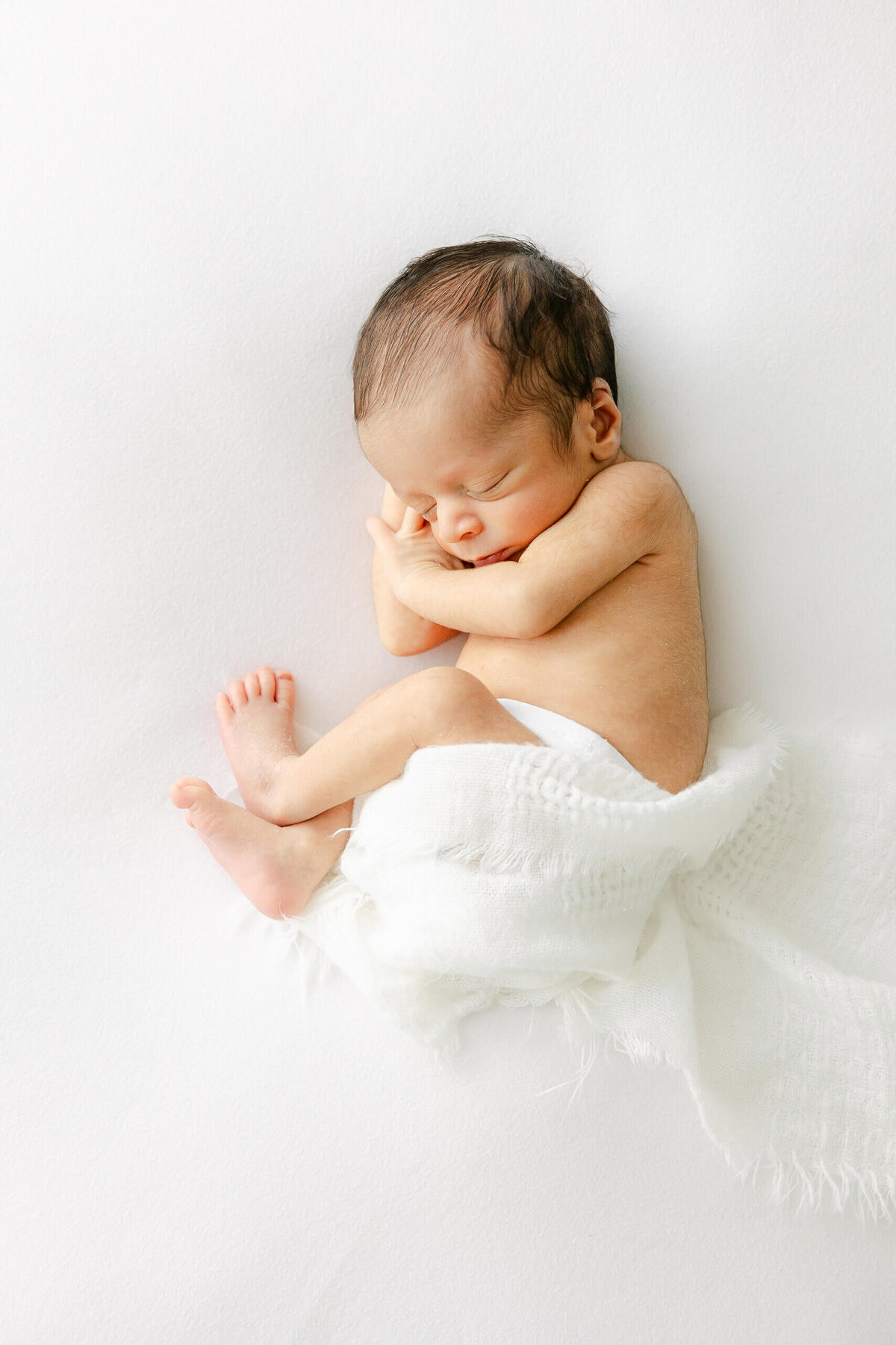 a newborn baby curled up while sleeping