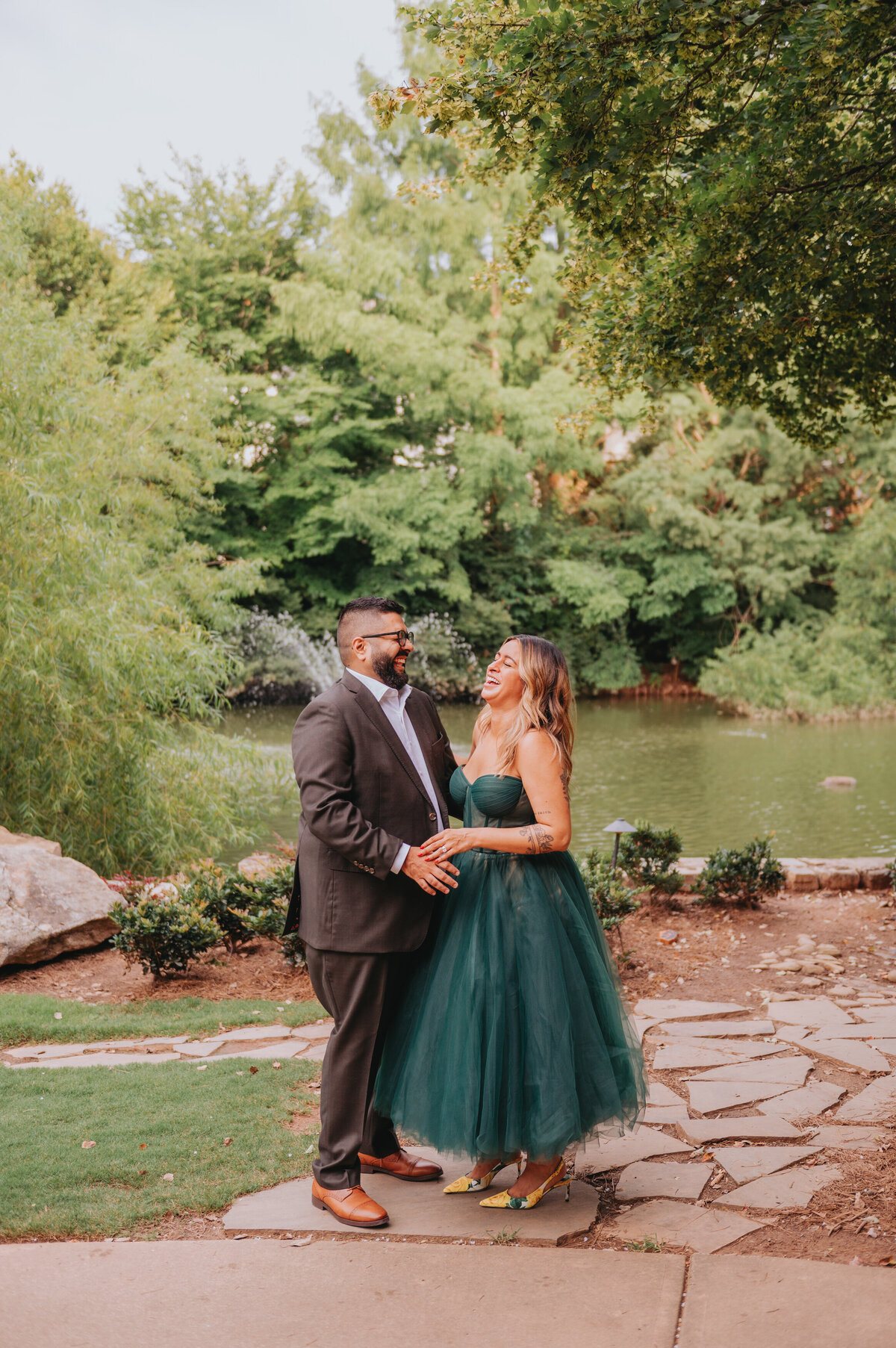 Two people stand outdoors laughing during their elopement