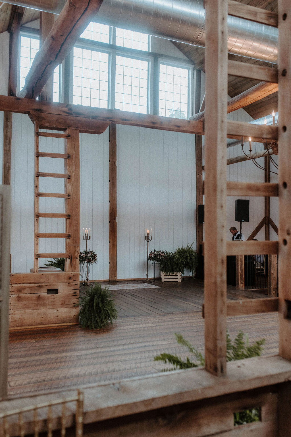 modern barn wedding ceremony set with green plants and candle holders with white shiplap walls and barn beams at Willowbrook wedding venue