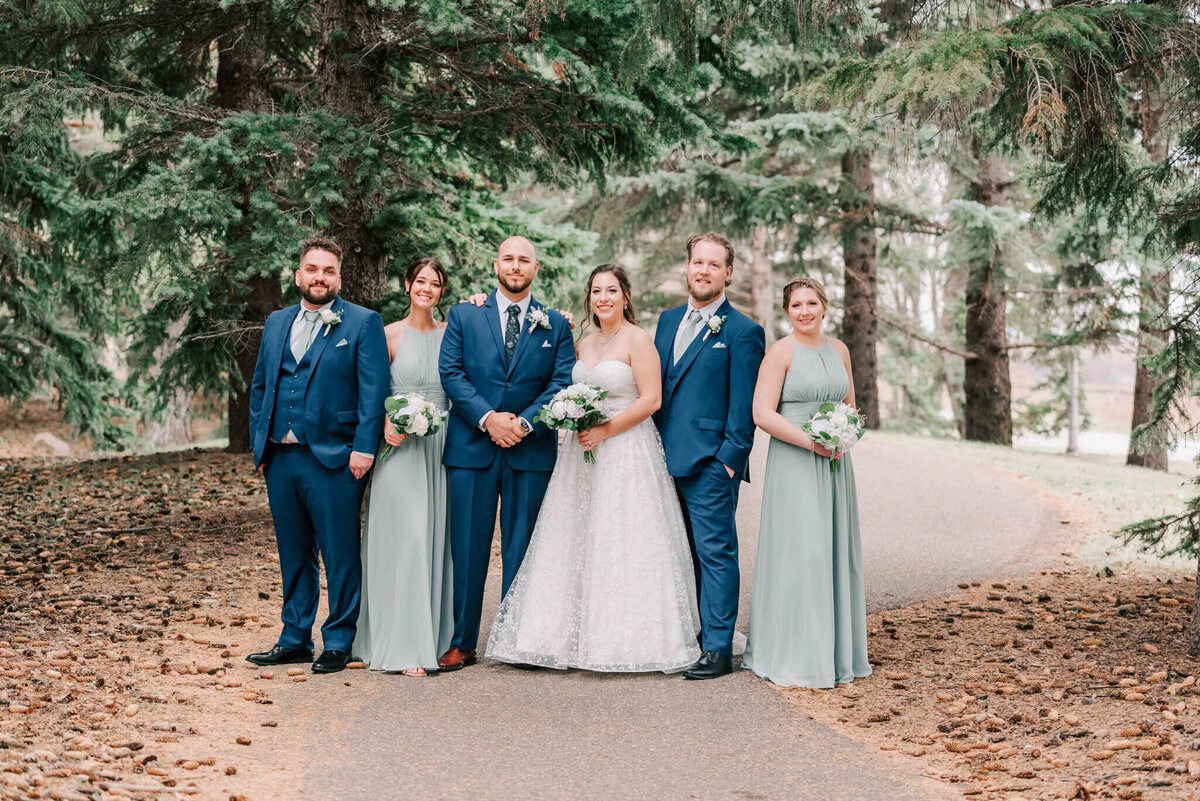 Wedding party poses for a portrait on a path on campus. 