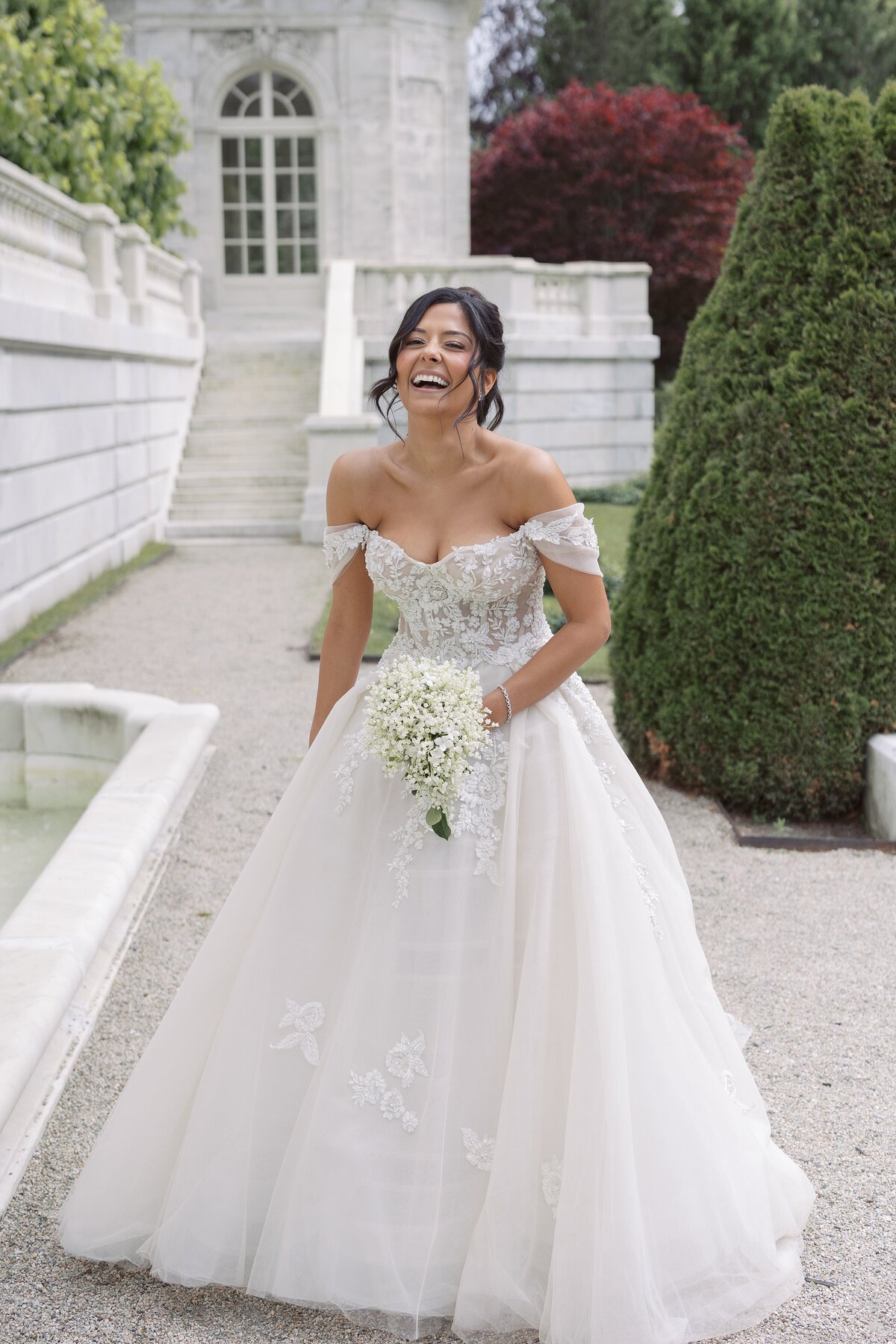 Bride laughs in wedding dress in the garden of The Elms mansion.