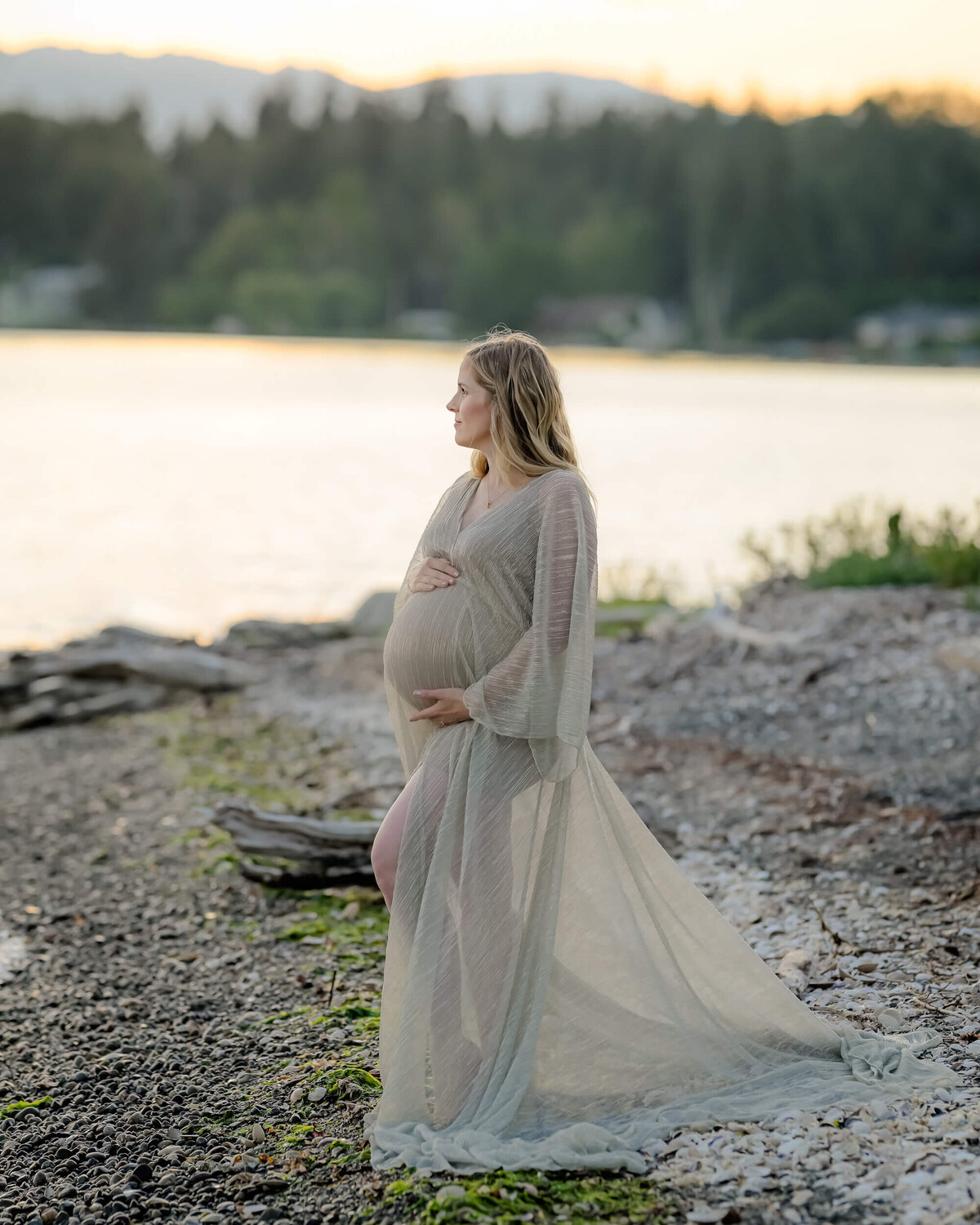 Mom-to-be wears a sheer golden dress on a PNW beach during the golden hour. Photographed by E. Benecki Photography.