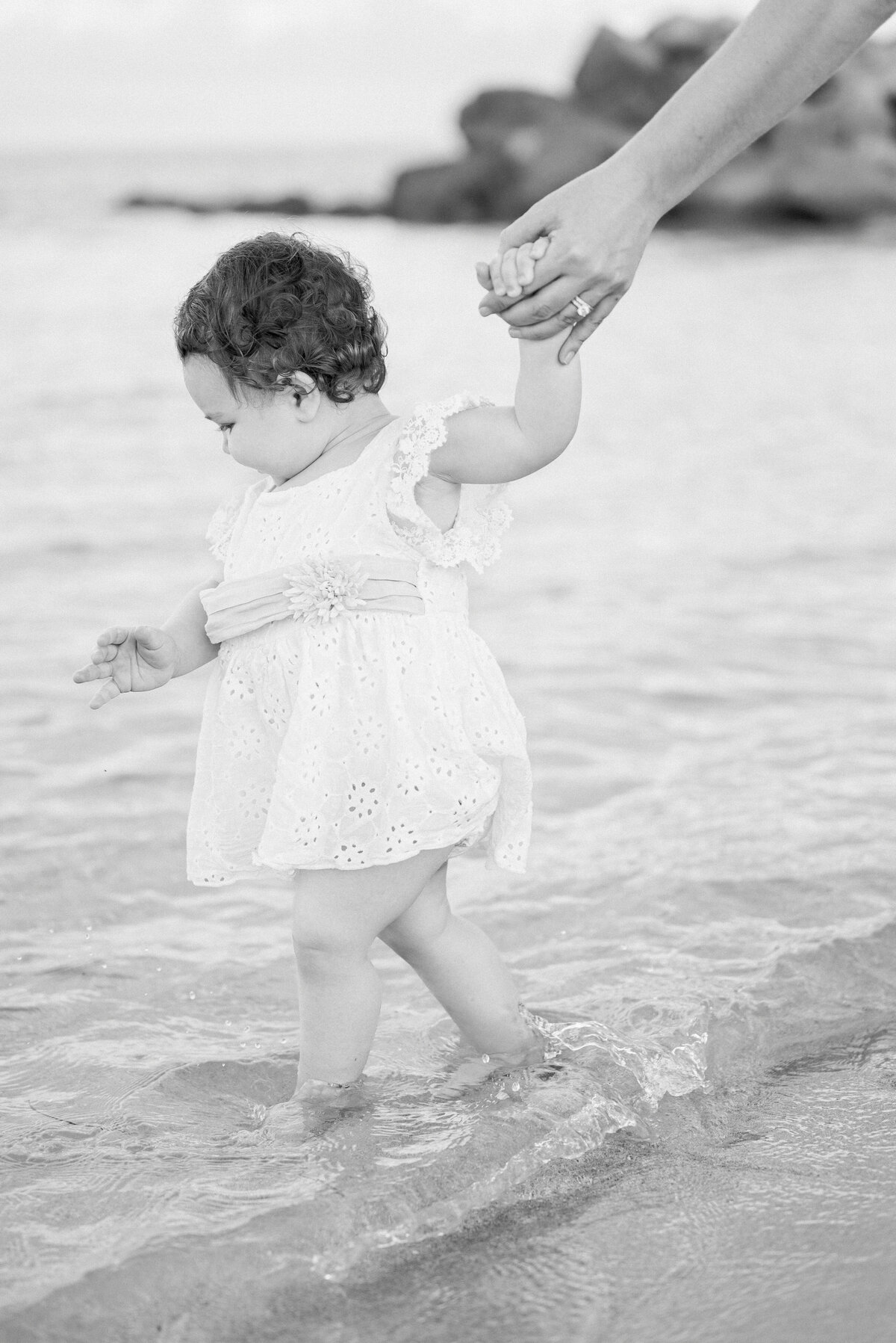 Black and white photo baby girl walking on the beach