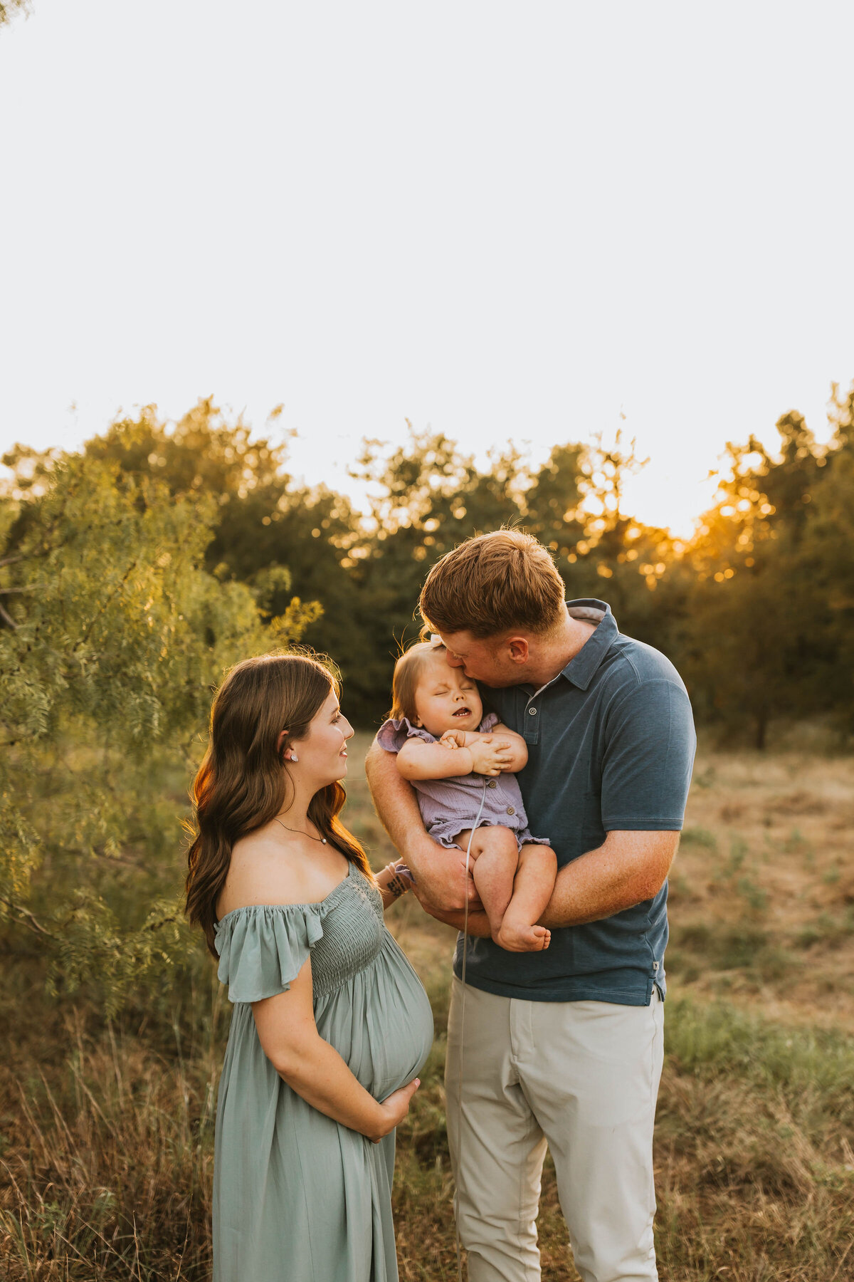 expecting mother standing next to her partner and son