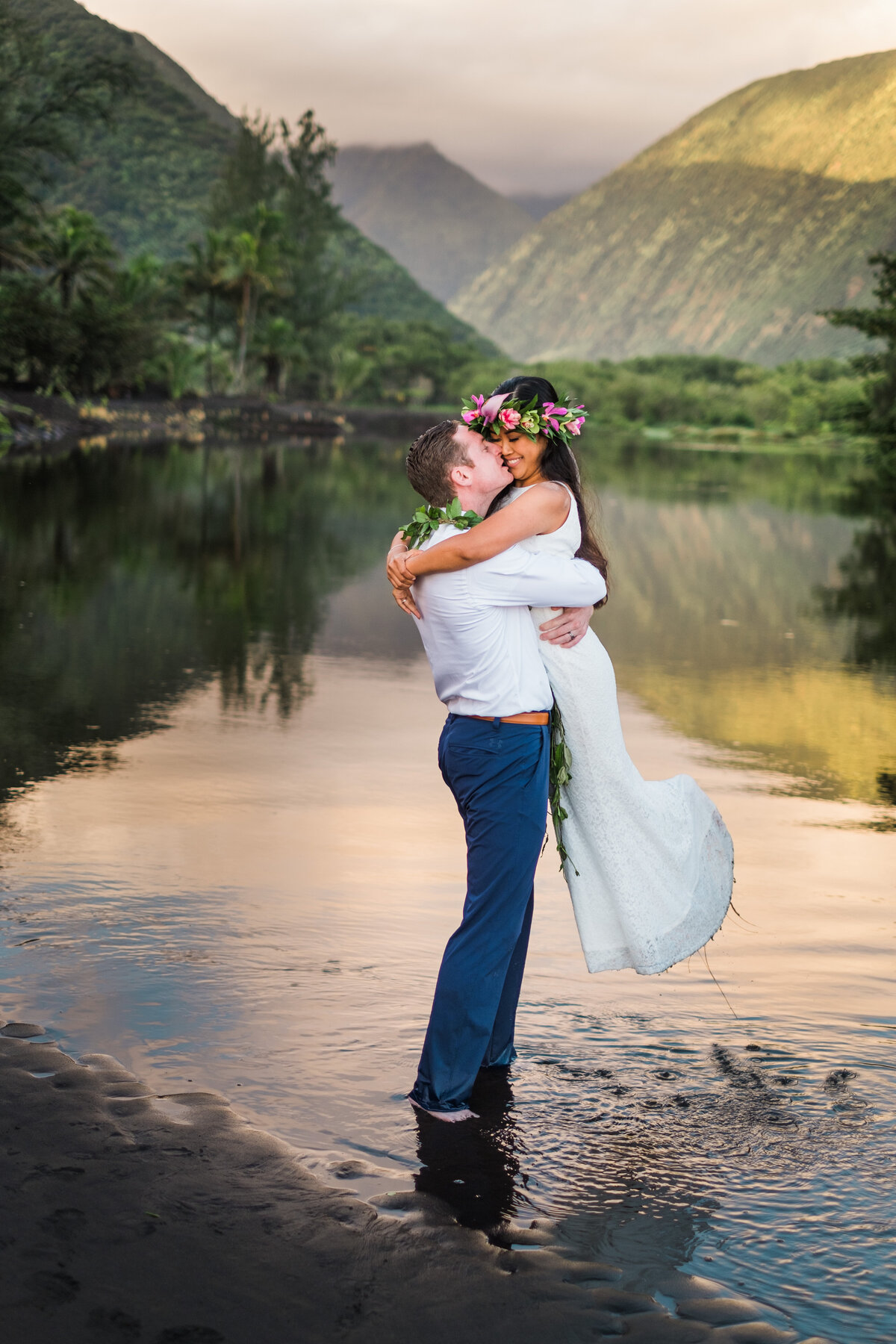 Big Island Wedding Planner. Groom picking up bride in a river at sunrise in the famous valley on the Big Island of Hawaii.