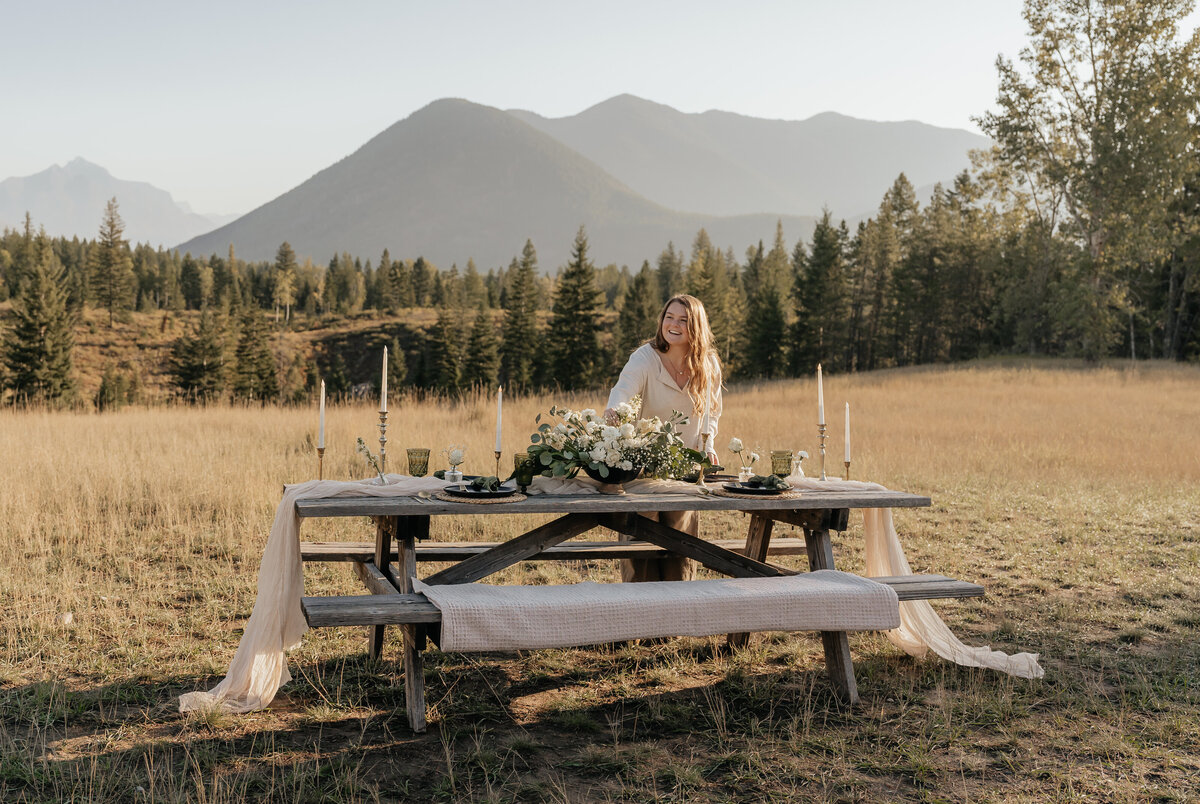 Montana Elopement Planner poses while setting up a tablescape near Glacier National Park.