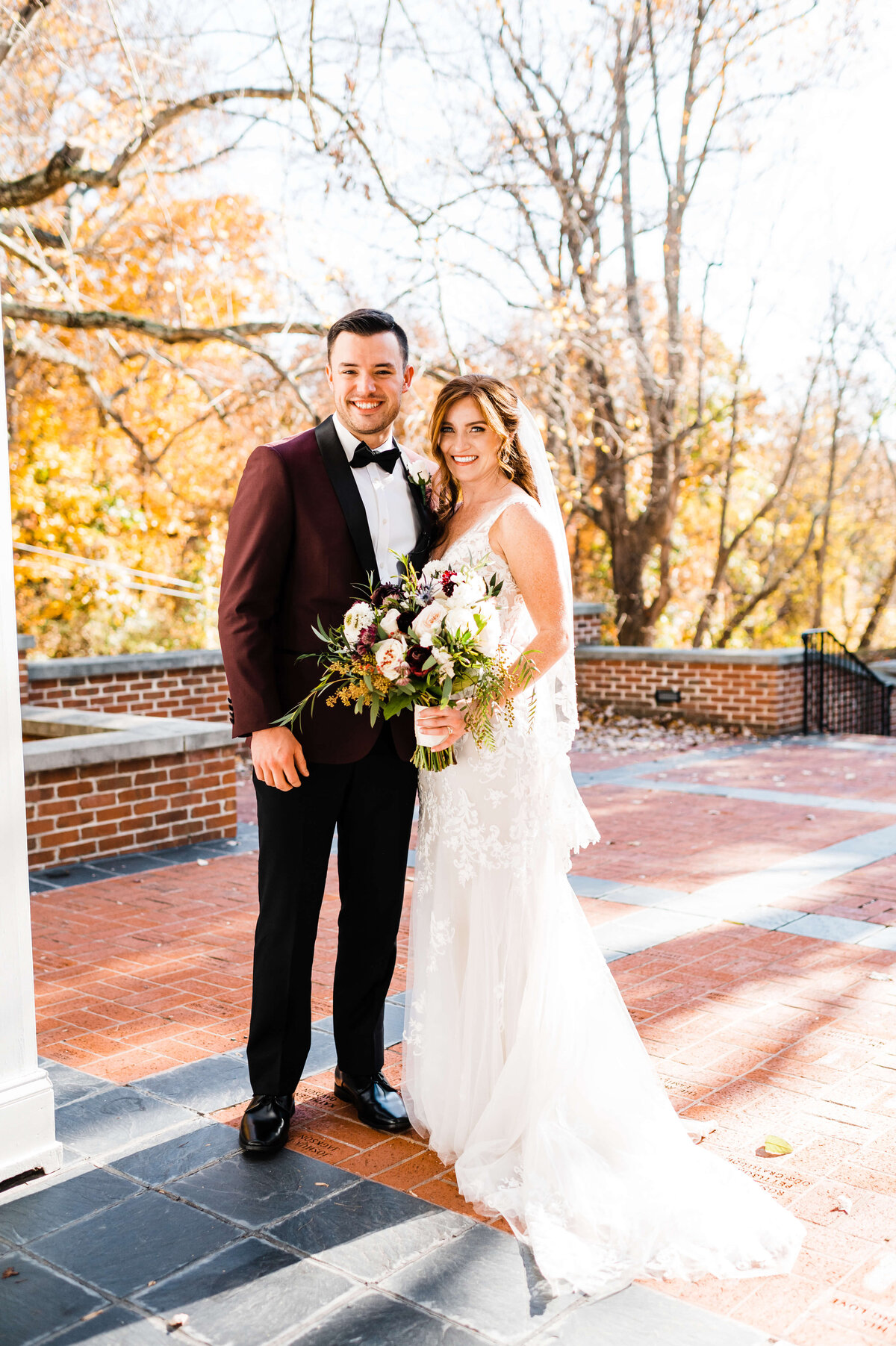 Bridal portraits outside among autumn trees with bride and groom posing together on a brick patio of Charlottesville wedding venues