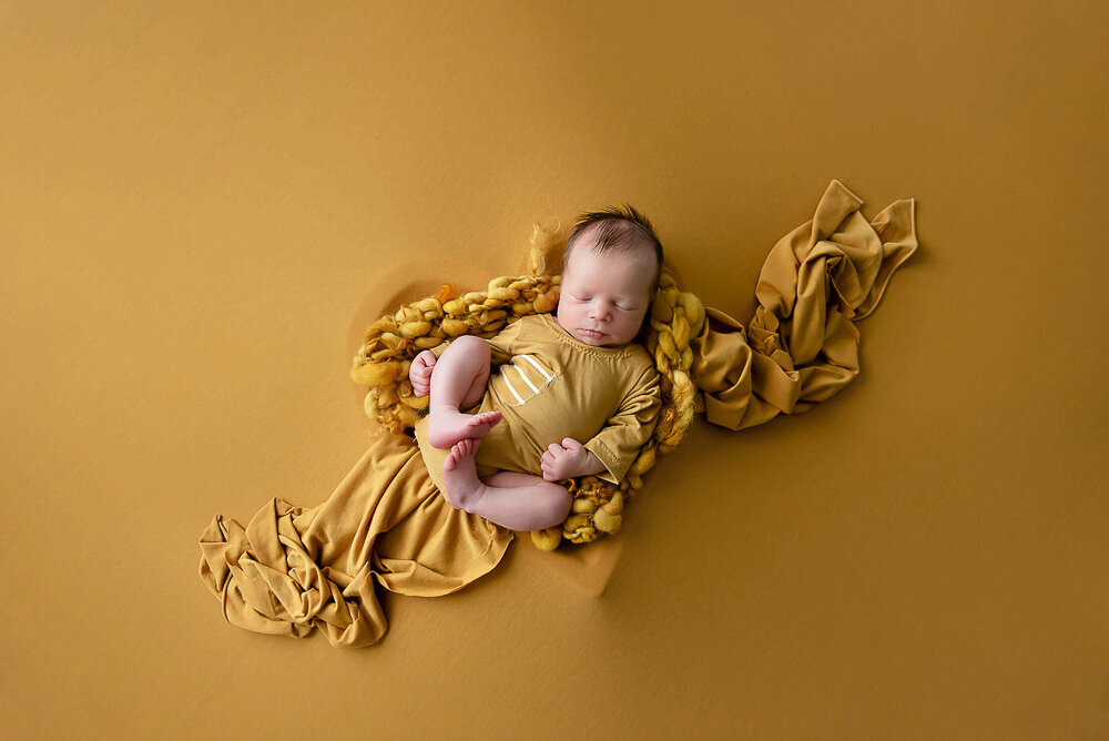 Baby boy in a yellow outfit on a yellow background.