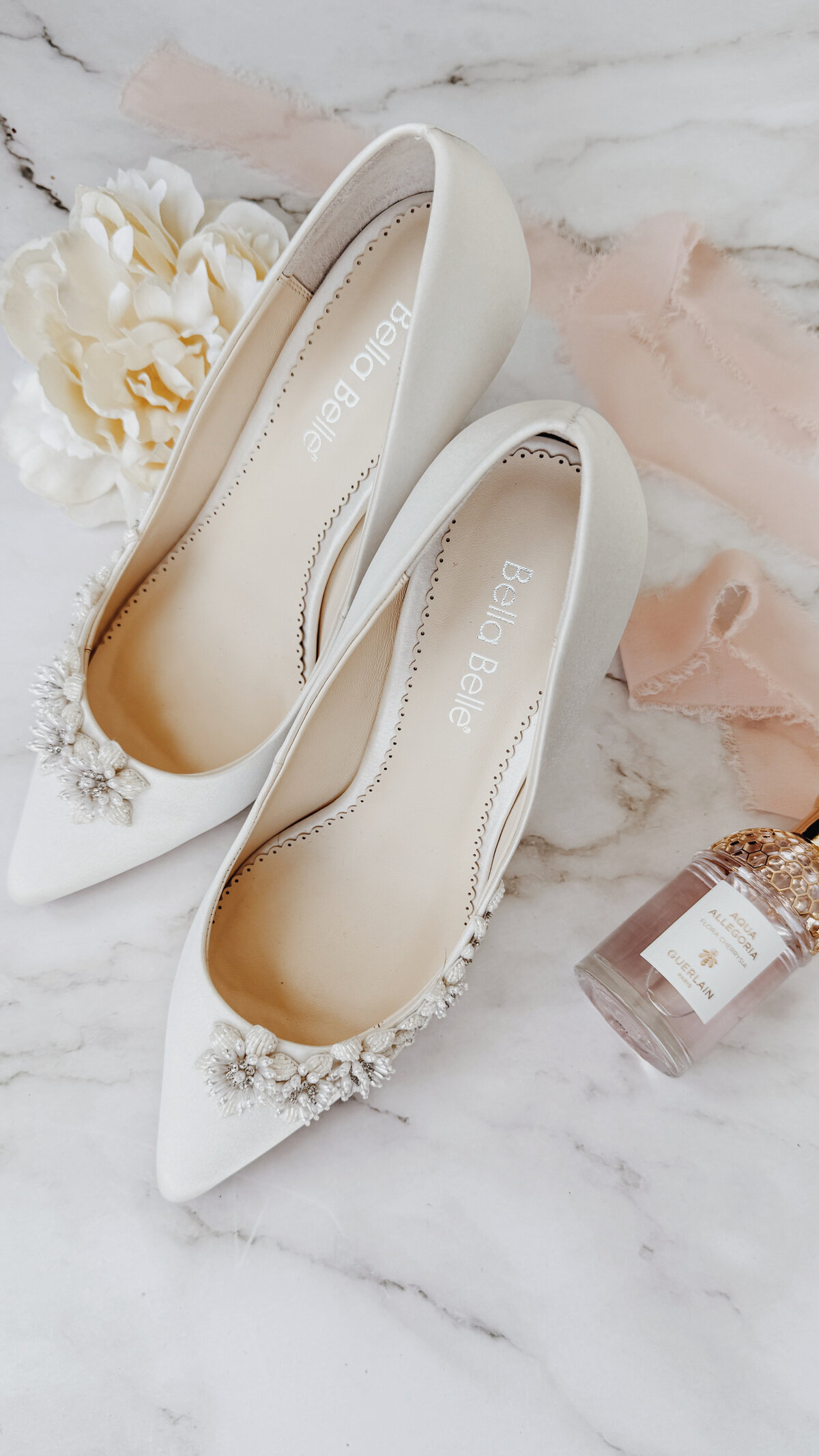 Bride Bella Belle shoes next to a champagne ring box with wedding and engagement rings on a lace veil at Lake San Marcos.
