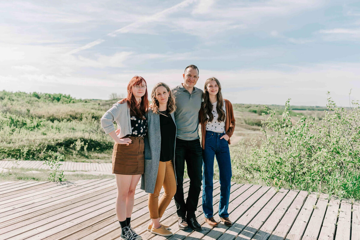 A family stands together on a boardwalk with Saskatchewan landscape behind them. 
