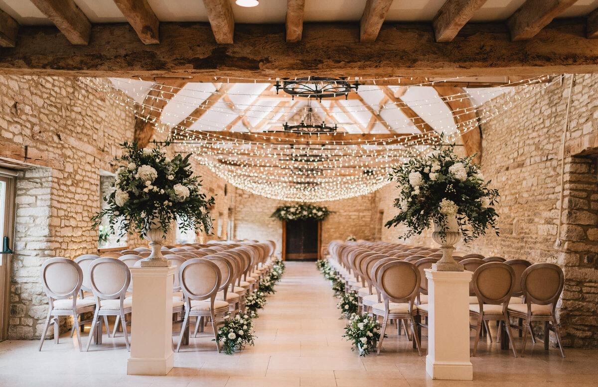Wedding ceremony in the Caswell House barn with large urns of flowers framing the aisle