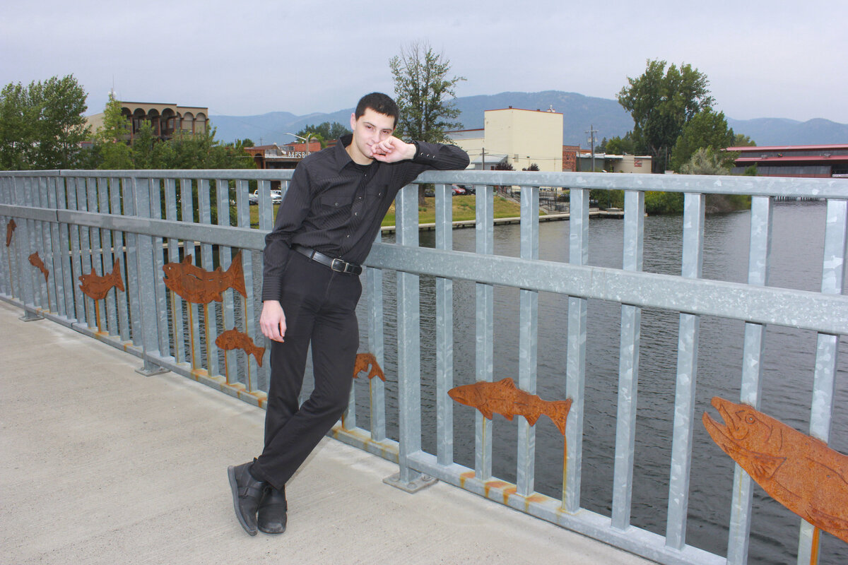 Man on bridge leaning on railing near river