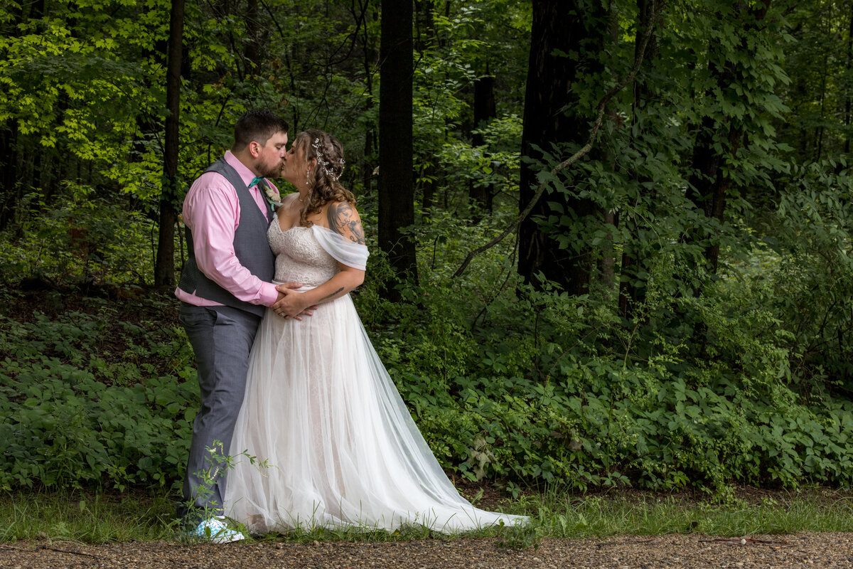 Kissing couple nestled in a deep green forest scene.