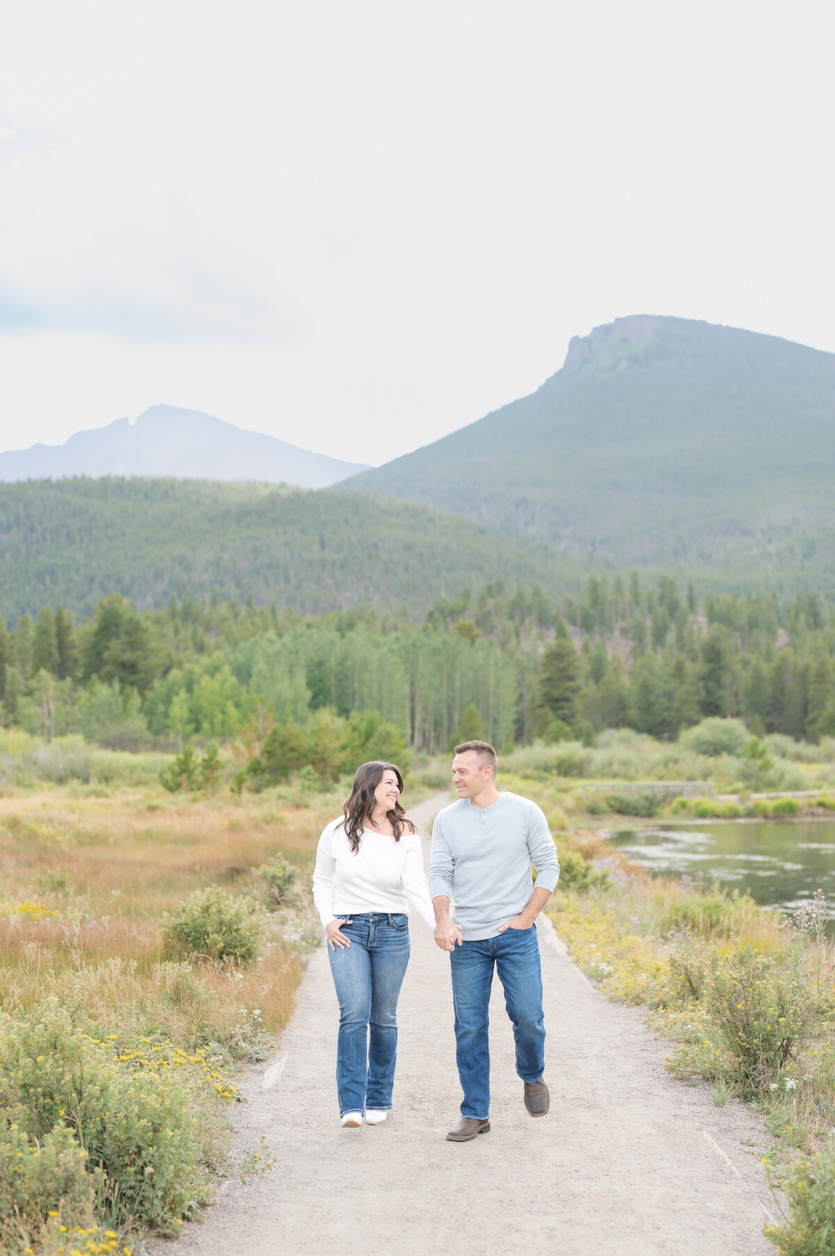 Couple walking together holding hands and laughing with Colorado mountain views behind them